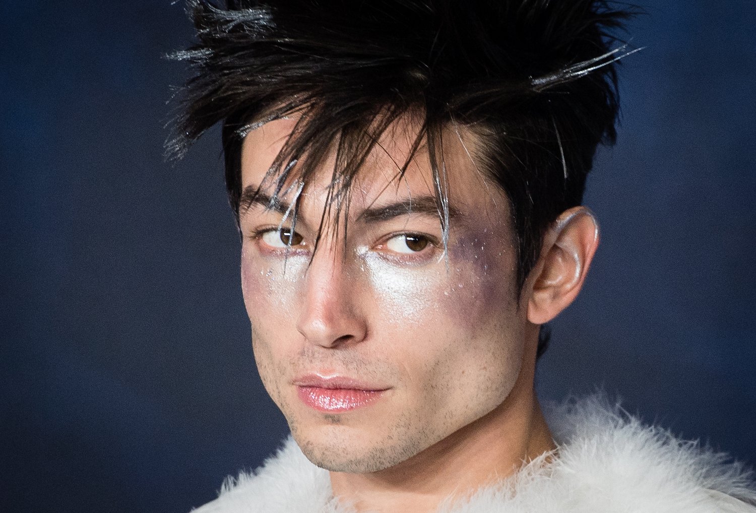 A close-up of Ezra Miller wearing white eye makeup at a premiere