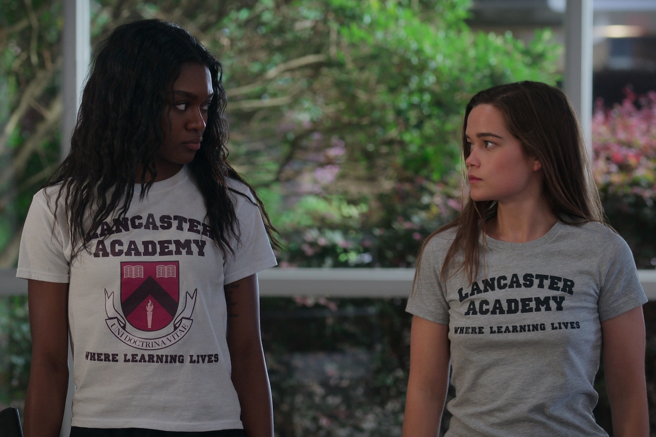 (L to R) Imani Lewis as Calliope, Sarah Catherine Hook as Juliette in 'First Kill' look each other wearing gym shirts.