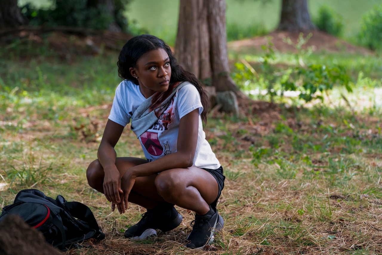 Imani Lewis as Calliope is crouched down in the woods looking up in 'First Kill'.