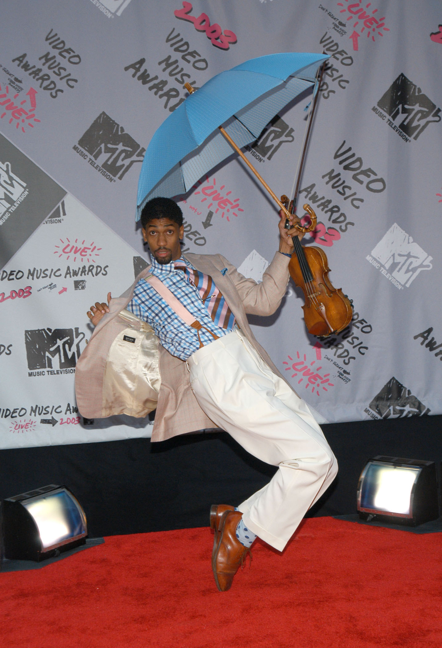 Diddy's assistant, Fonzworth Bentley, posing on his toes and holding an umbrella over his head on the red carpet