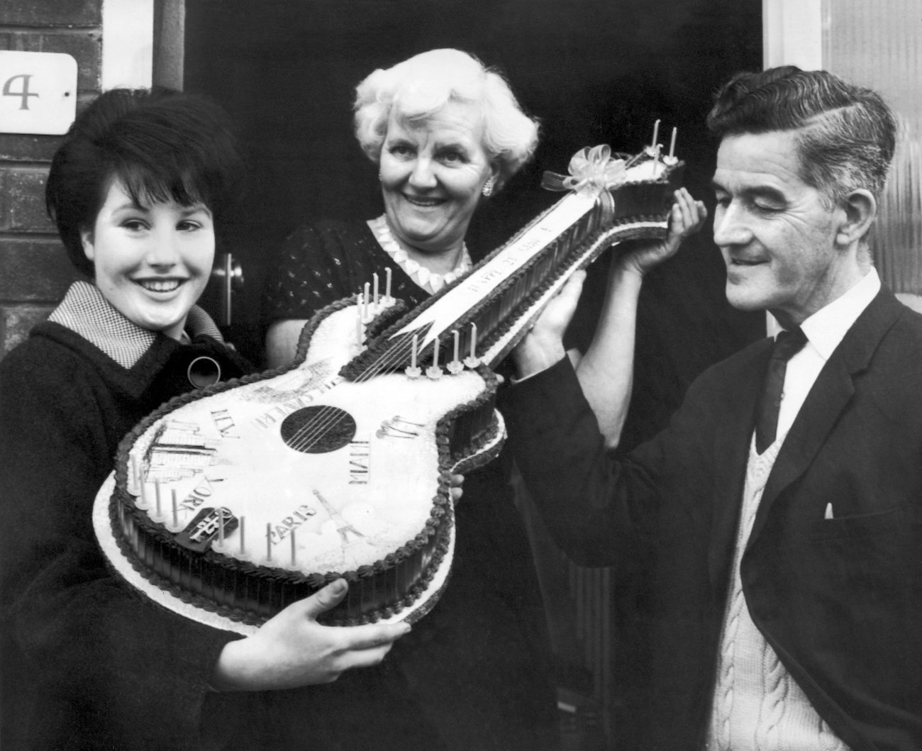 A fan presenting George Harrison's parents, Louise and Harold, with a cake for their son's 21st birthday in 1964.
