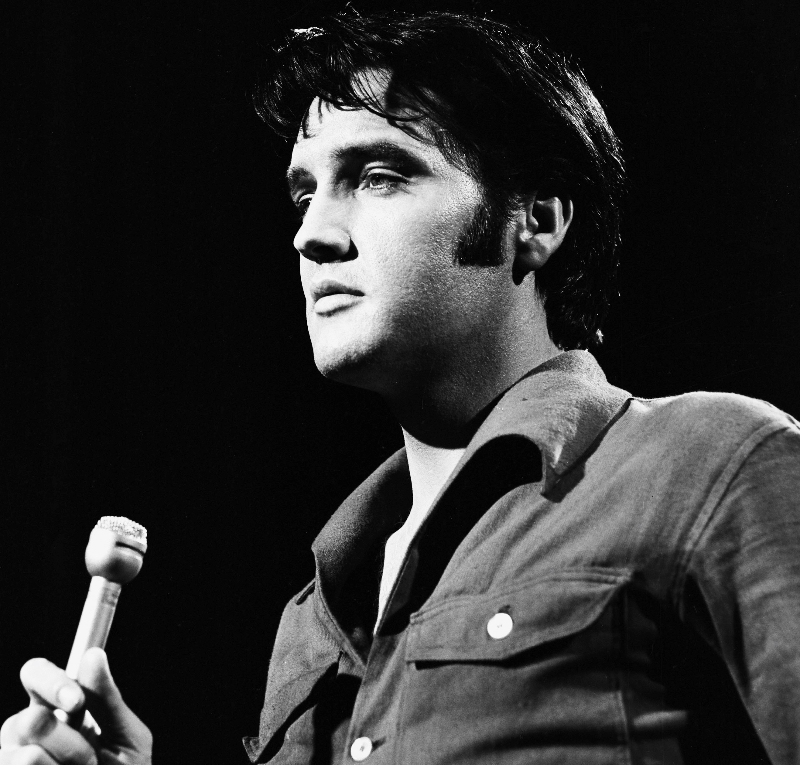 Elvis Presley singing songs into a microphone