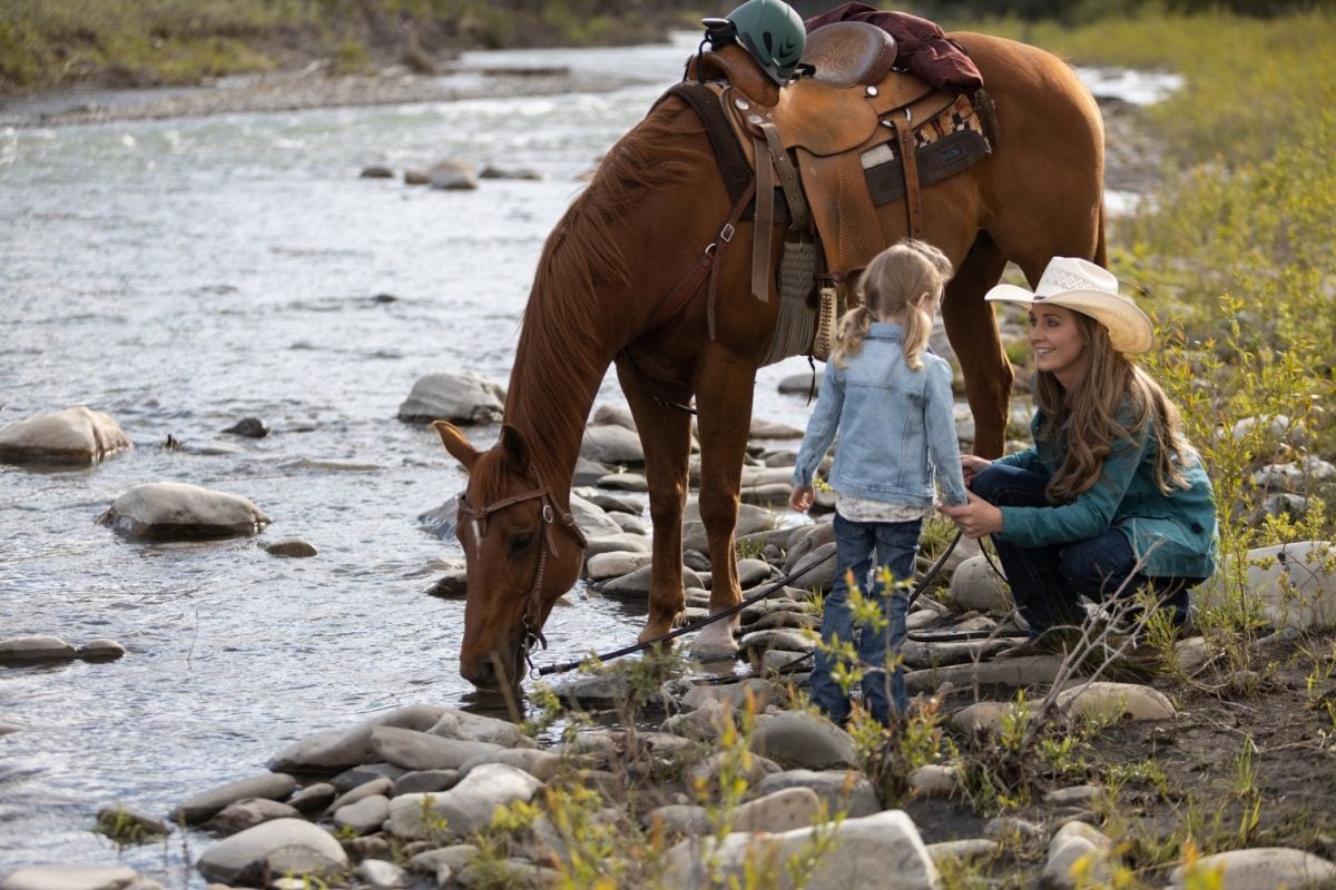 Amy and Lyndy with a chestnut horse next to a stream in season 15 of 'Heartland'
