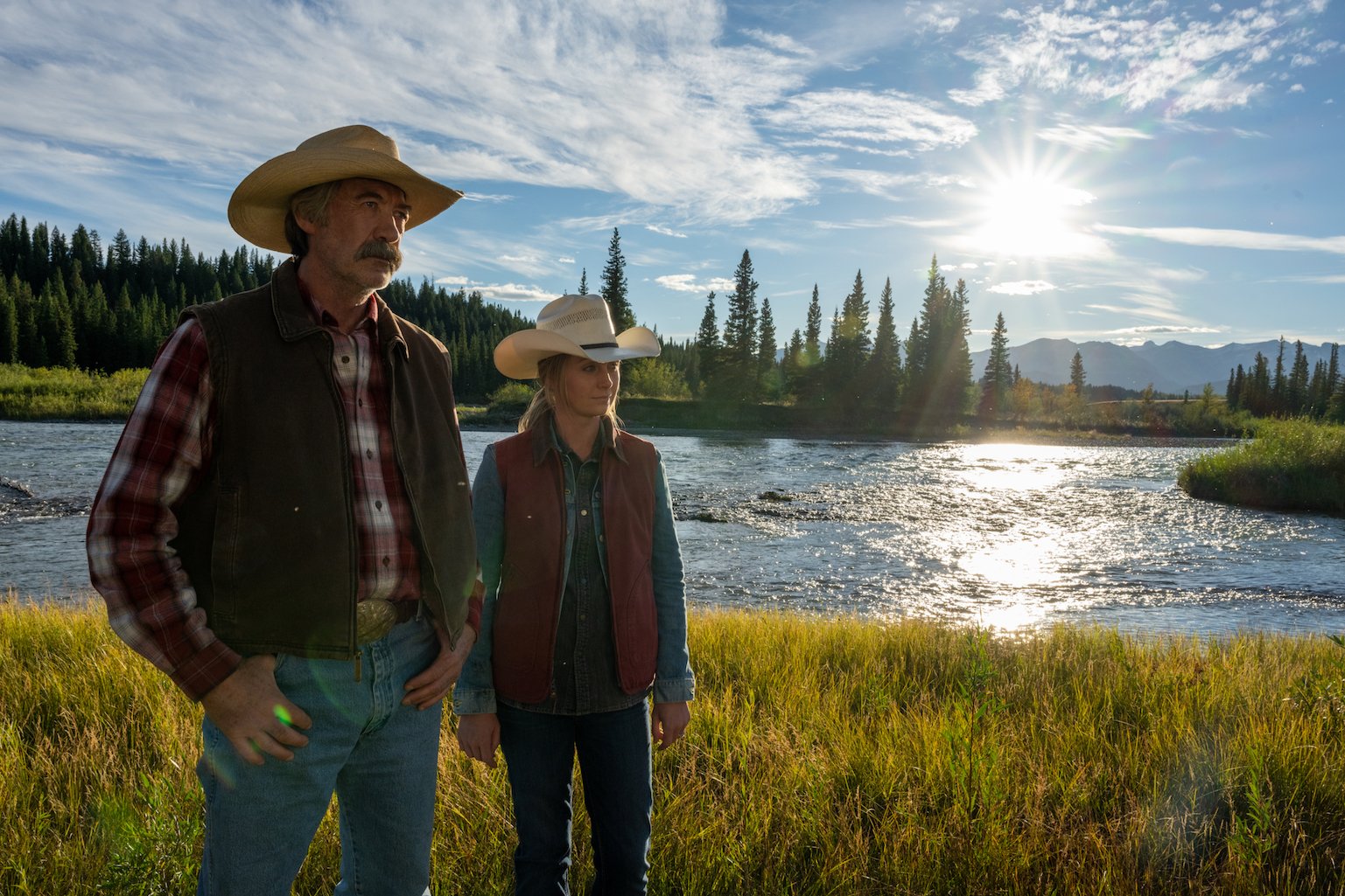 Amy Fleming and Jack Bartlett standing outside next to a lake in 'Heartland'