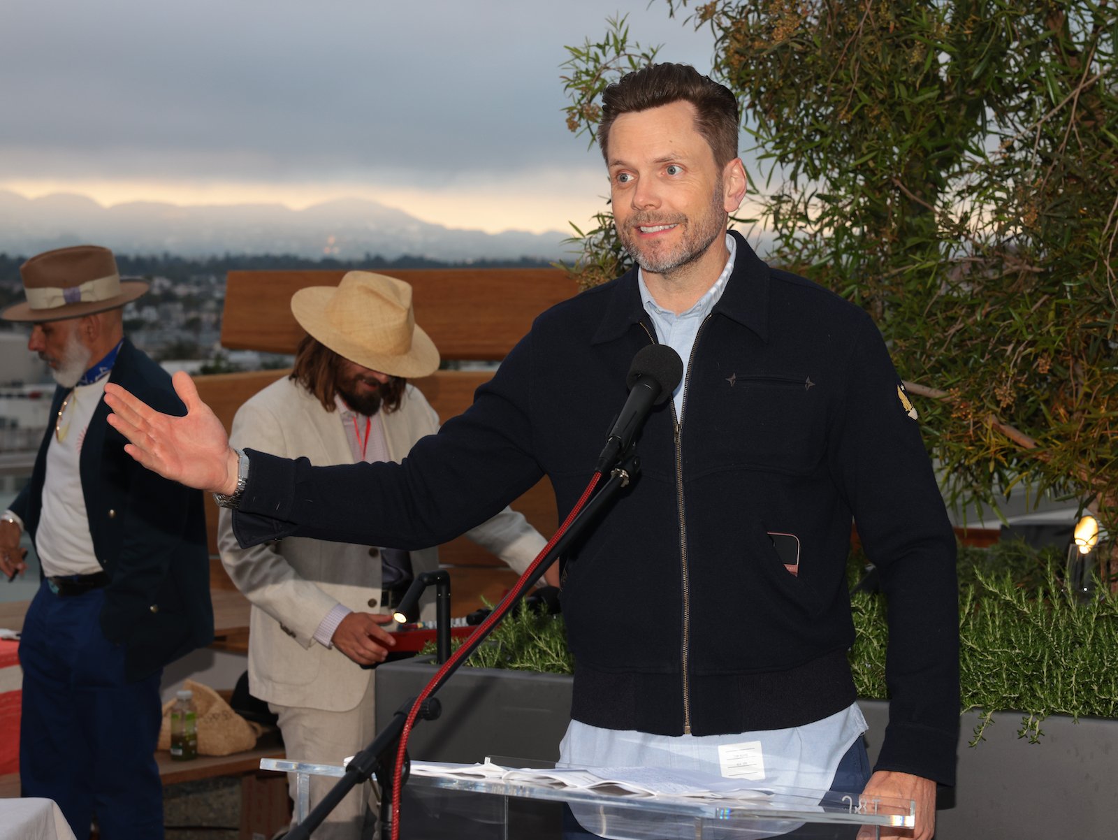 Joel McHale gestures to the side while presenting at the GO Campaign