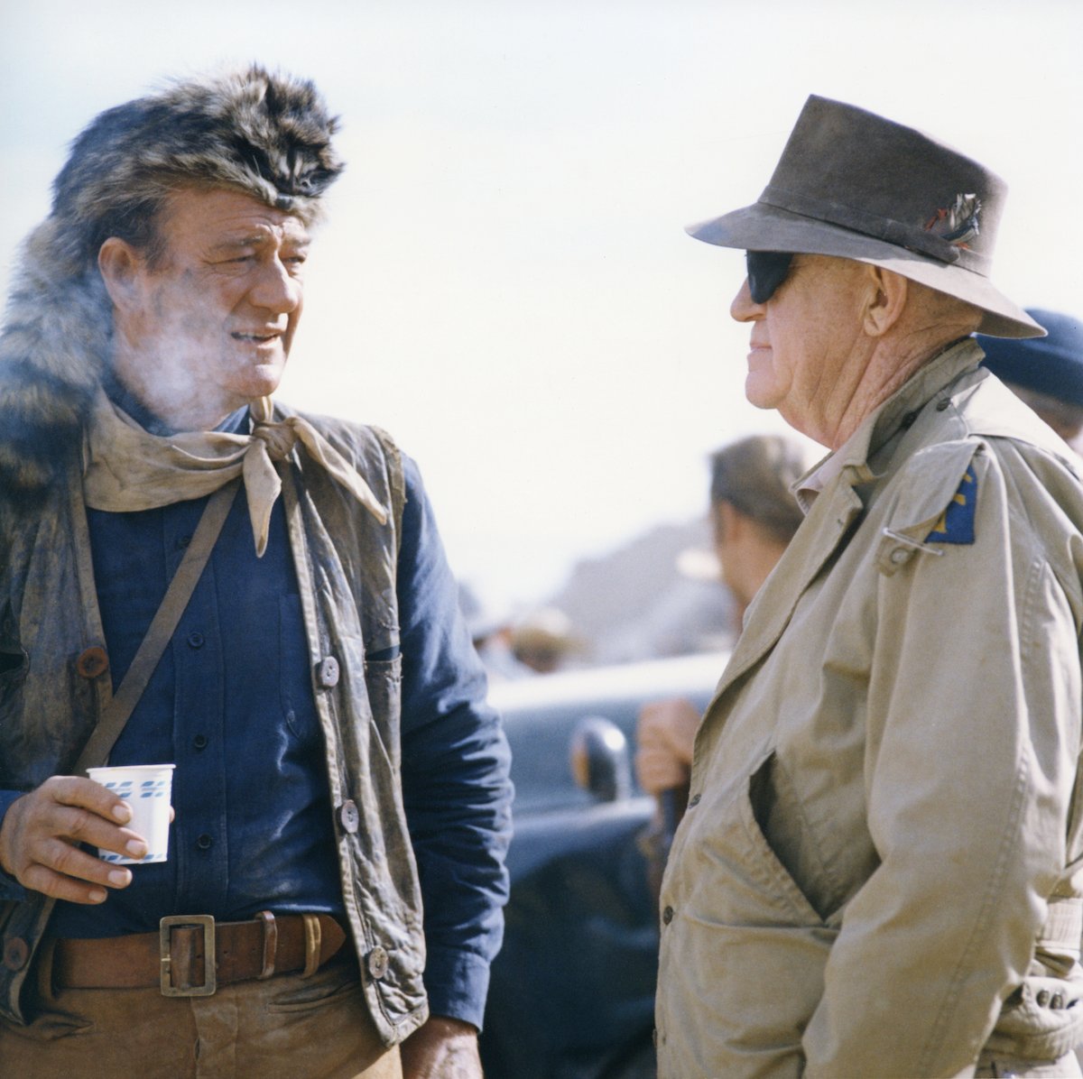 John Wayne holds a cup while mentor John Ford visits him on the set of 'The Alamo'