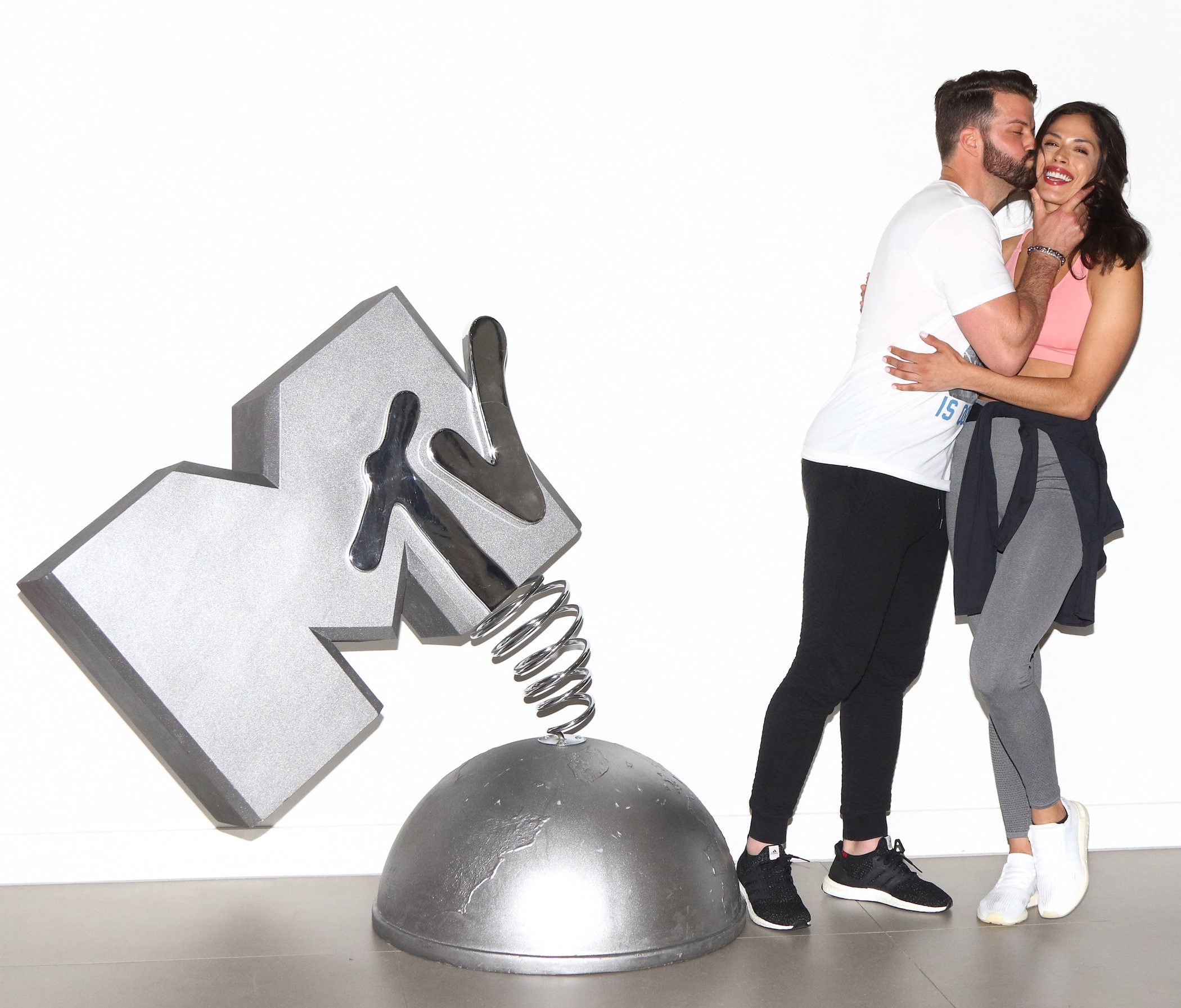 Johnny 'Bananas' Devenanzio and Nany Gonzalez from MTV 's 'The Challenge' Season 38 hugging each other next to an MTV statue
