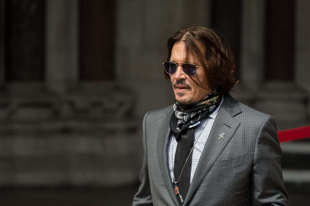 Johnny Depp posing while wearing a grey suit.