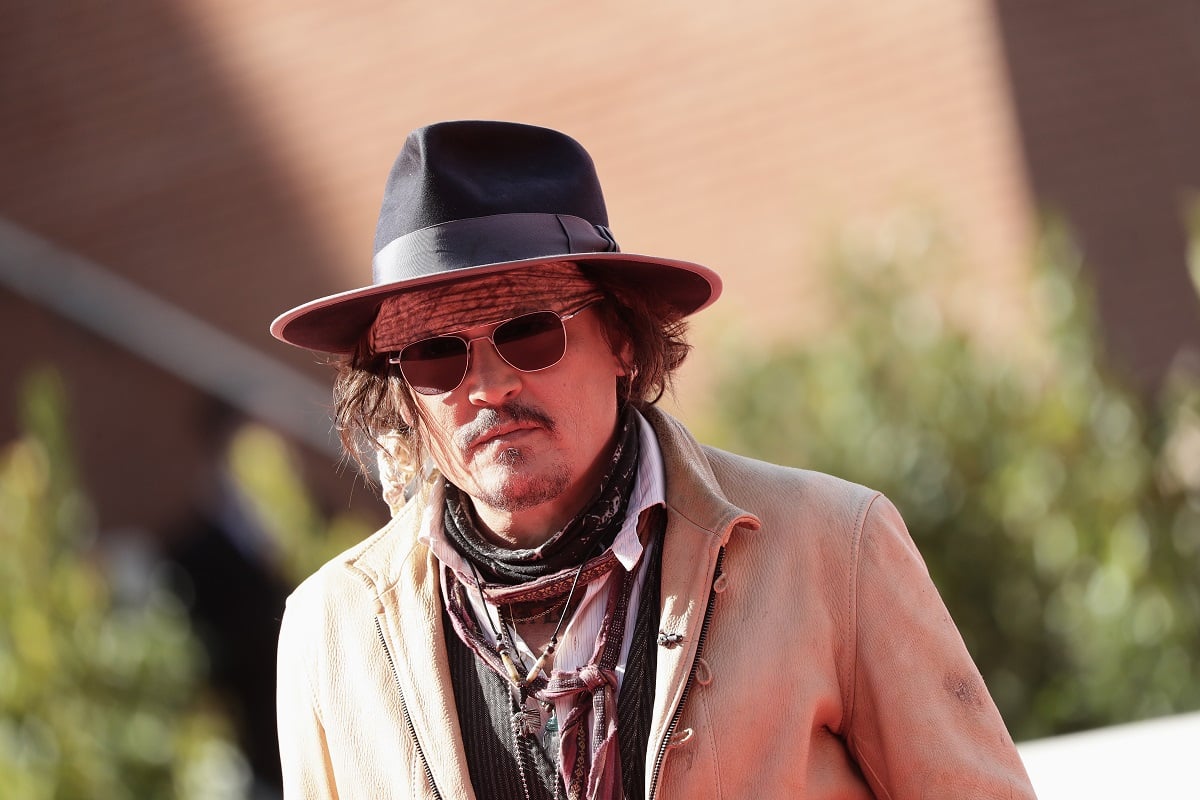 Johnny Depp posing while wearing a hat and sunglasses.