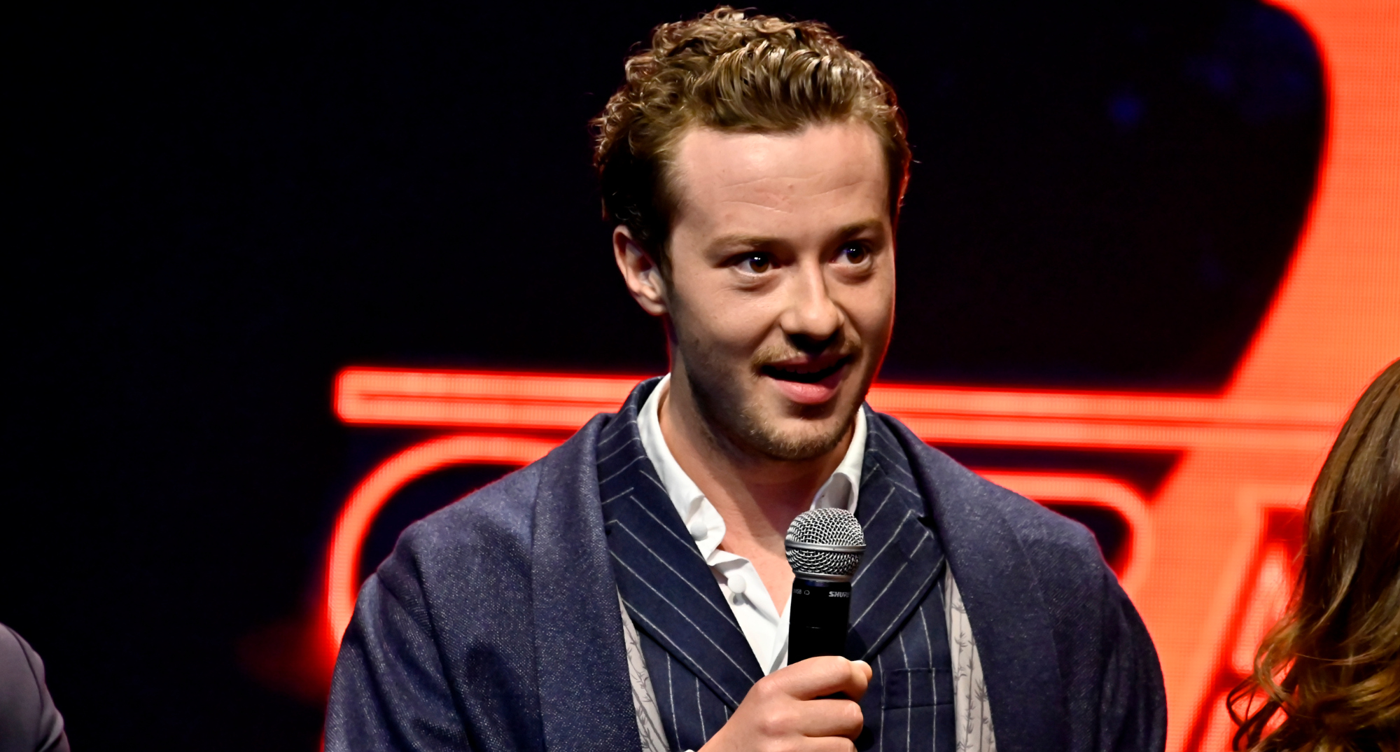 Joseph Quinn plays Eddie Munson 'Stranger Things' Season 4 holding a microphone.