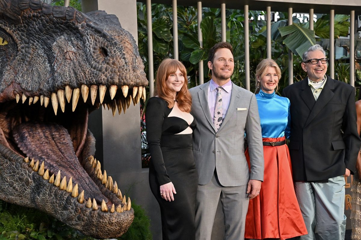 'Jurassic World: Dominion' cast members Bryce Dallas Howard, Chris Pratt, Laua Dern, and Jeff Goldblum pose next to a dinosaur statue.
