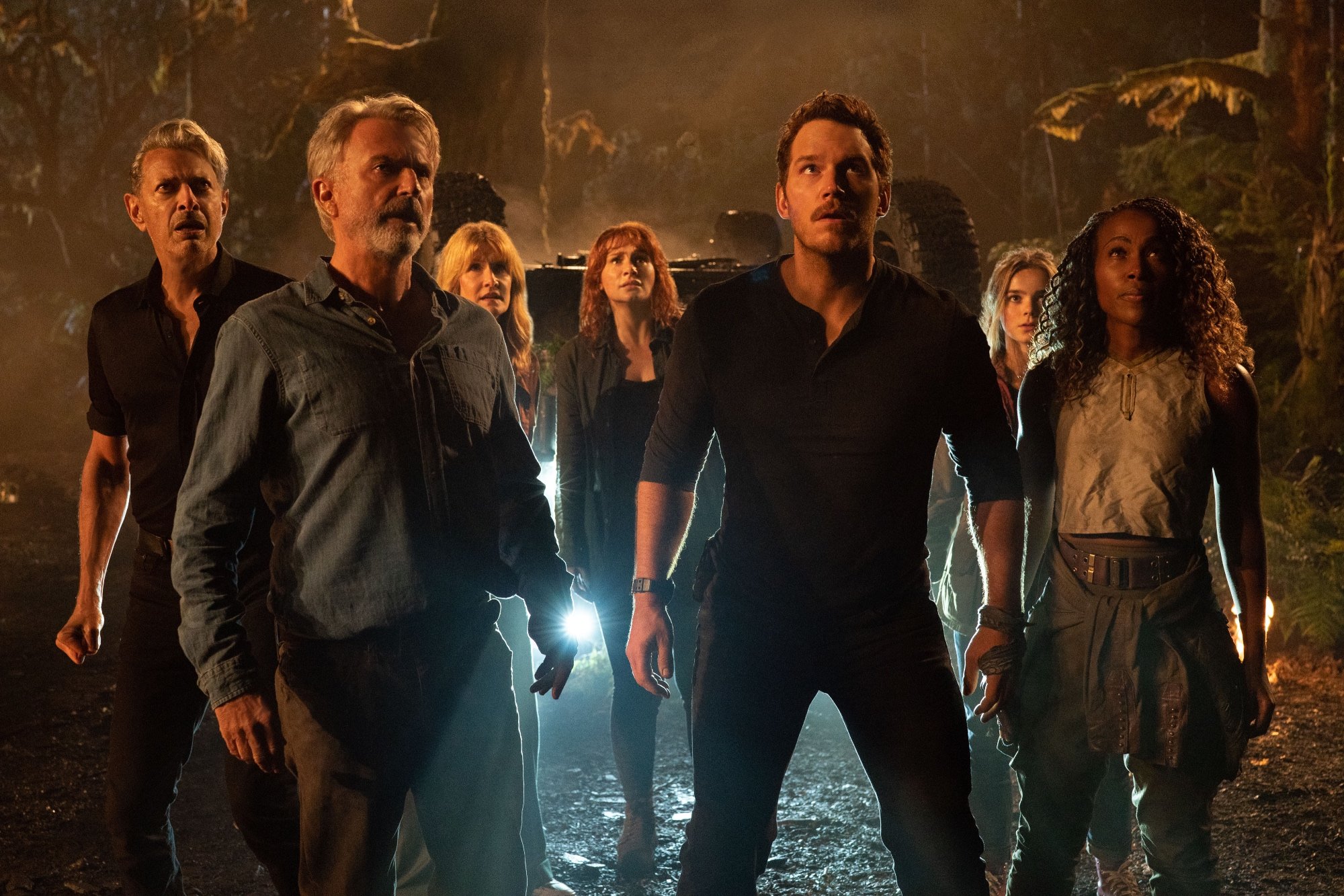 'Jurassic World Dominion' Jeff Goldblum as Dr. Ian Malcolm, Sam Neill as Dr. Alan Grant, Laura Dern as Dr. Ellie Sattler, Chris Pratt as Owen Grady, Isabella Sermon as Maisie Lockwood, and DeWanda Wise as Kayla Watts looking shocked looking up with a flipped over car behind them