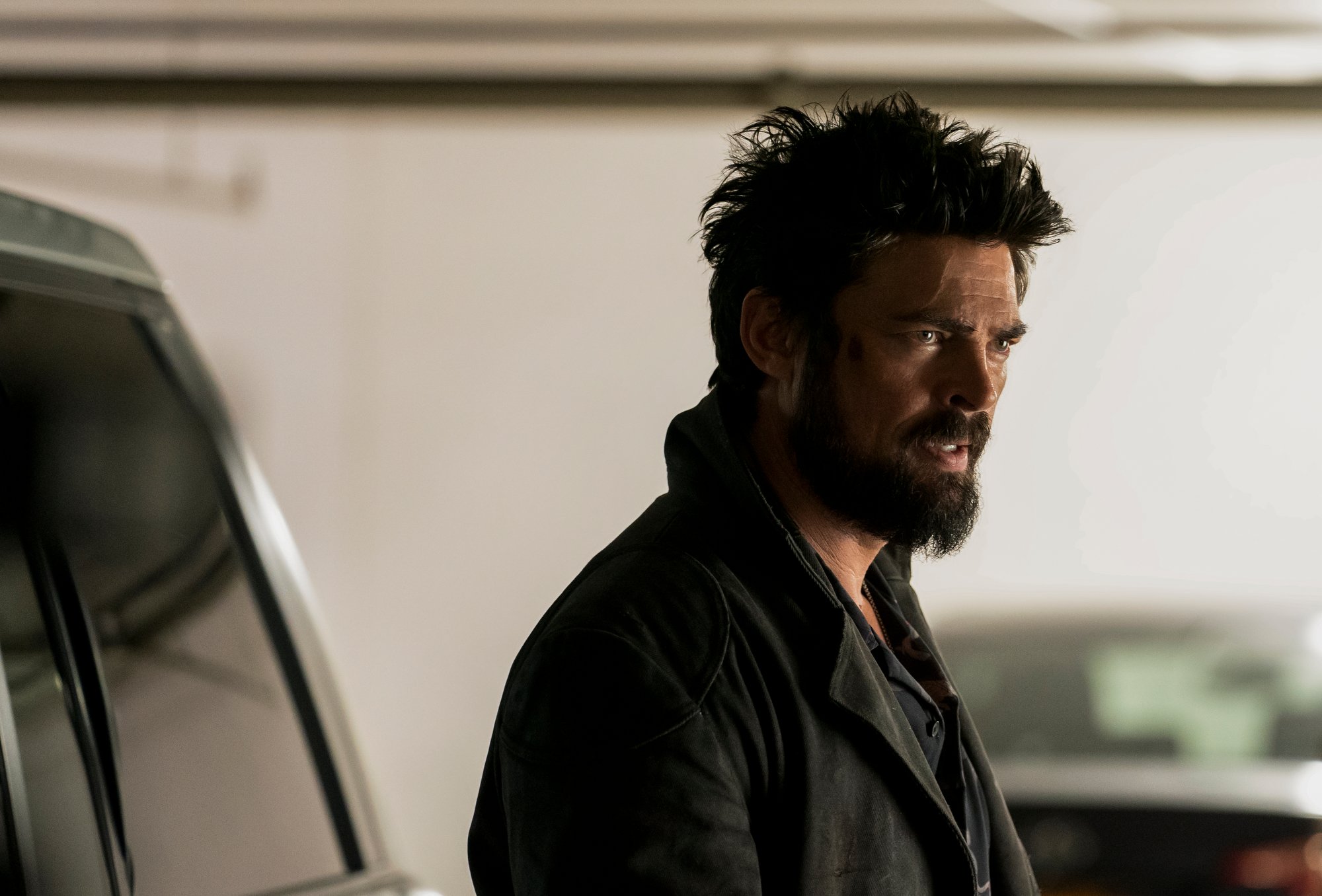 Karl Urban as Billy Butcher in 'The Boys,' which will present its characters with 1 major question in season 3. He's wearing a black coat and looks angry.