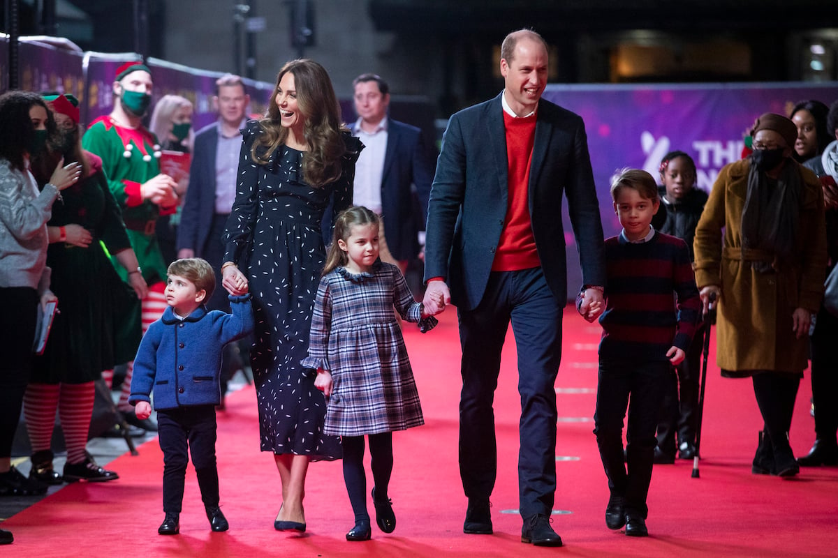 Kate Middleton and Prince William walk with their three children, who a royal author says there could be more photos of because of Meghan Markle and Prince Harry