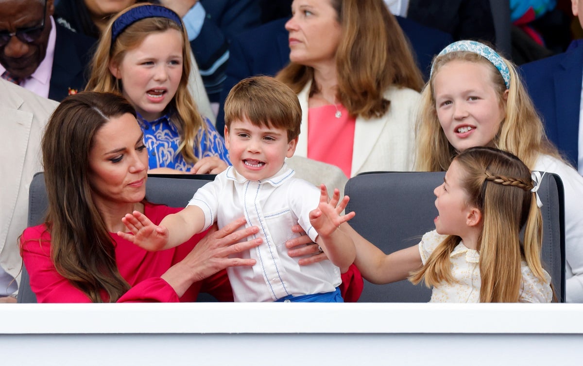 Kate Middleton holding Prince Louis as Princess Charlotte tries to grab his arm