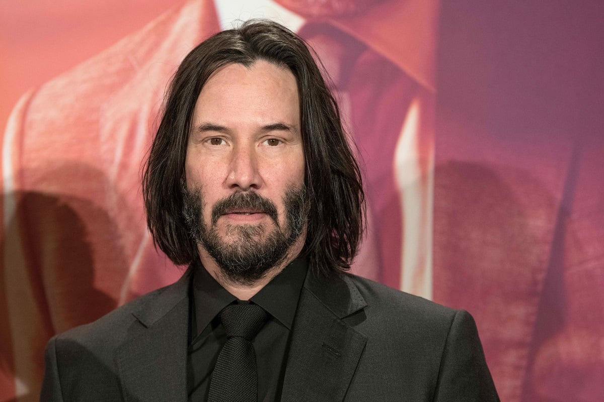 Keanu Reeves posing while wearing a black suit.