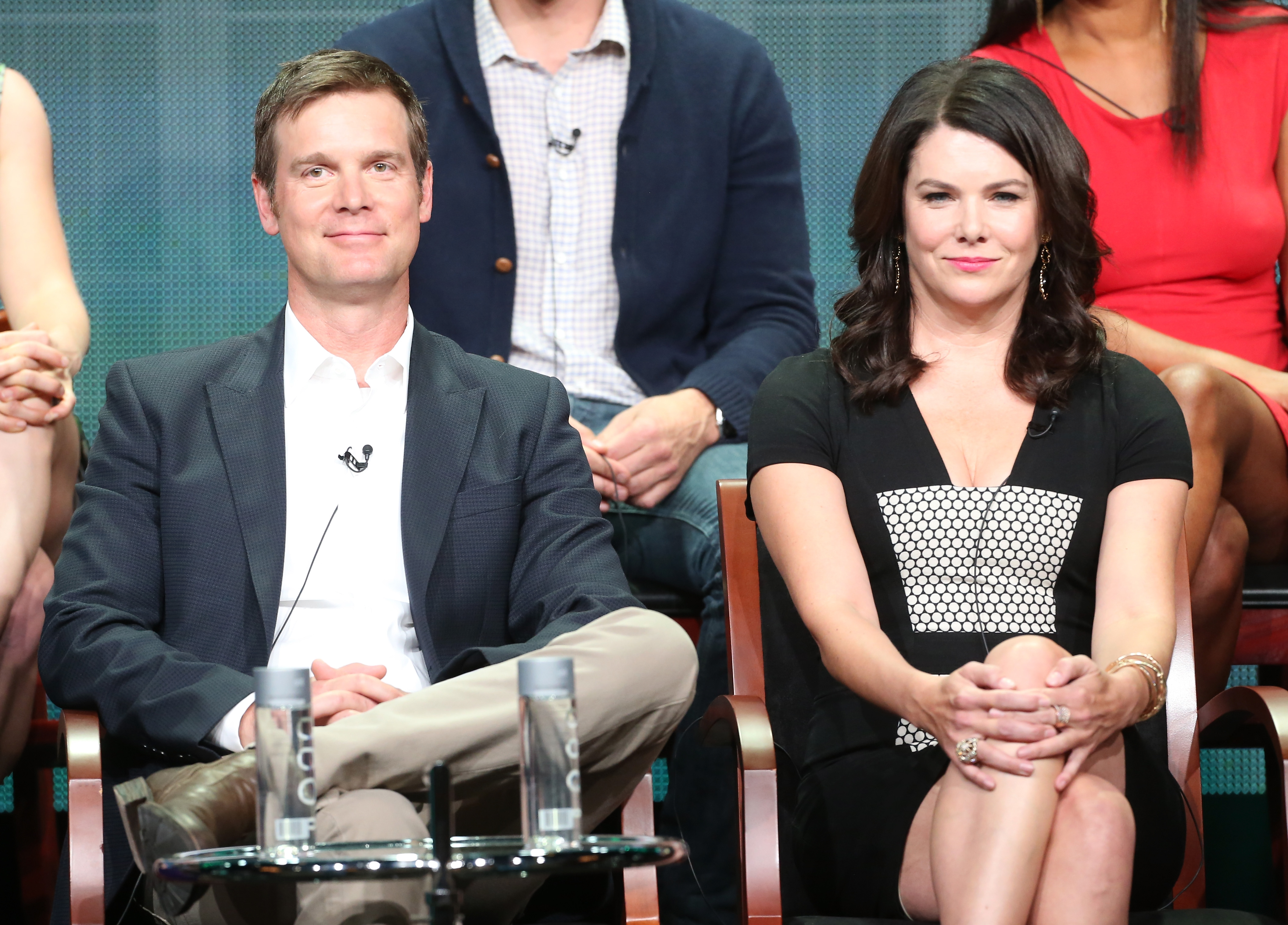 Peter Krause and Lauren Graham smiling and sitting next to each other on stage at an event for the series 'Parenthood.'
