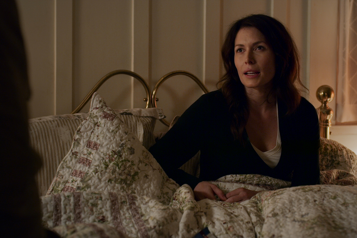 Lauren Hammersley as Charmaine Roberts sitting in a bed looking stressed in 'Virgin River'