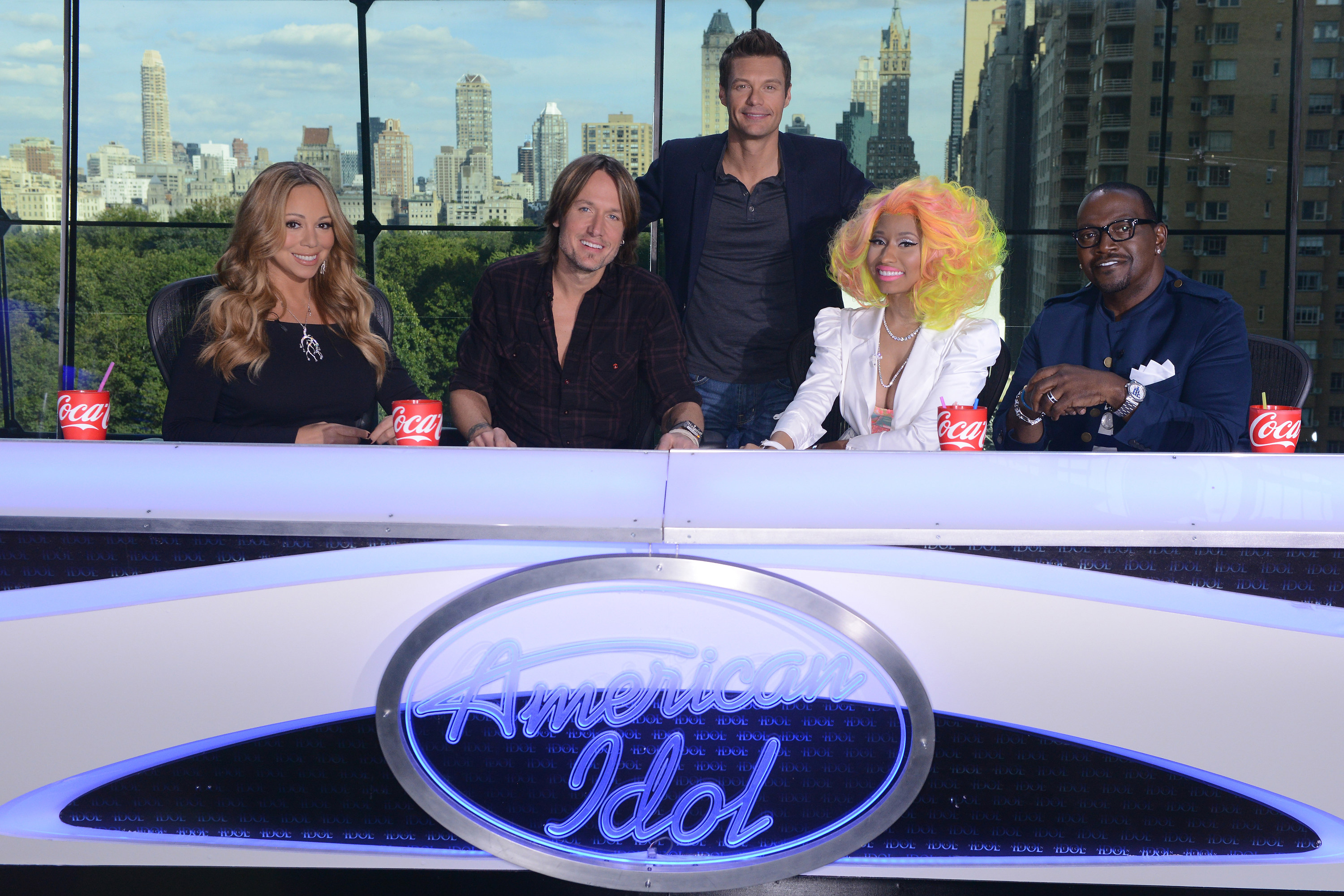 Mariah Carey, Keith Urban, Nicki Minaj, and Randy Jackson sit at the 'American Idol' desk. Ryan Seacrest stands behind them.