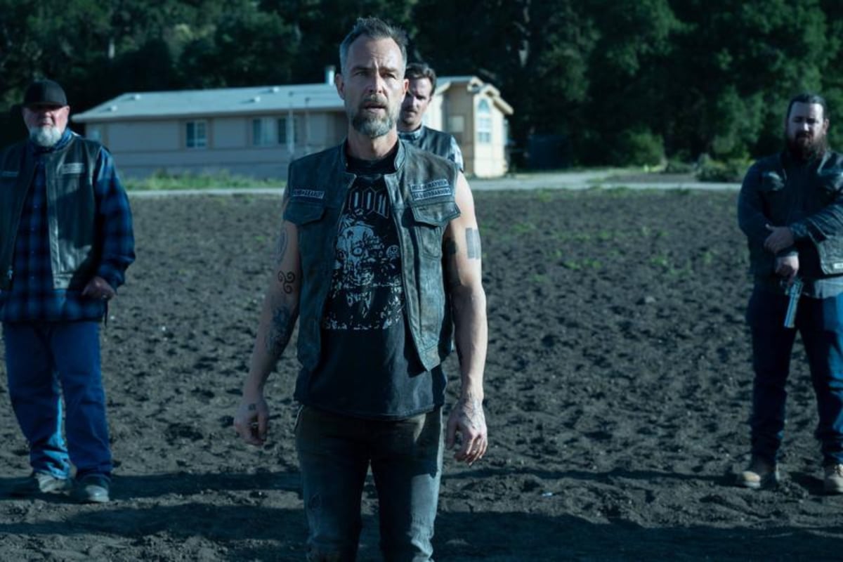 JR Bourne as Isaac Packer in Mayans MC Season 4. Isaac stands outside wearing a Sons of Anarchy vest. 