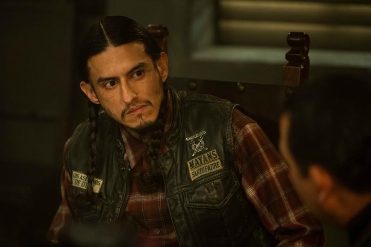 Richard Cabral as Coco in Mayans MC Season 4. Coco sits with Alvarez wearing his Mayans MC kutte.