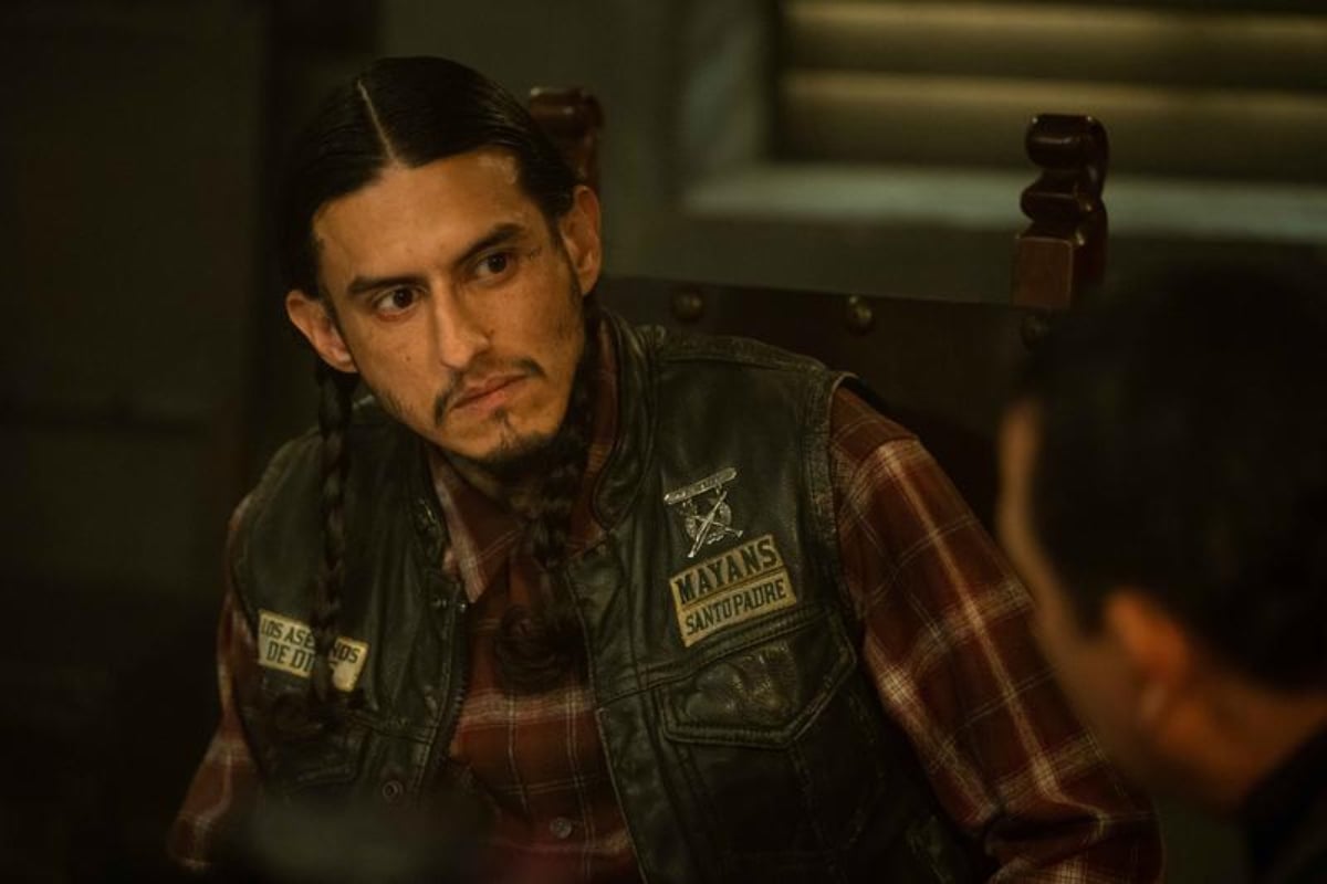 Richard Cabral as Coco in Mayans MC Season 4. Coco sits with Alvarez wearing his Mayans MC kutte. 