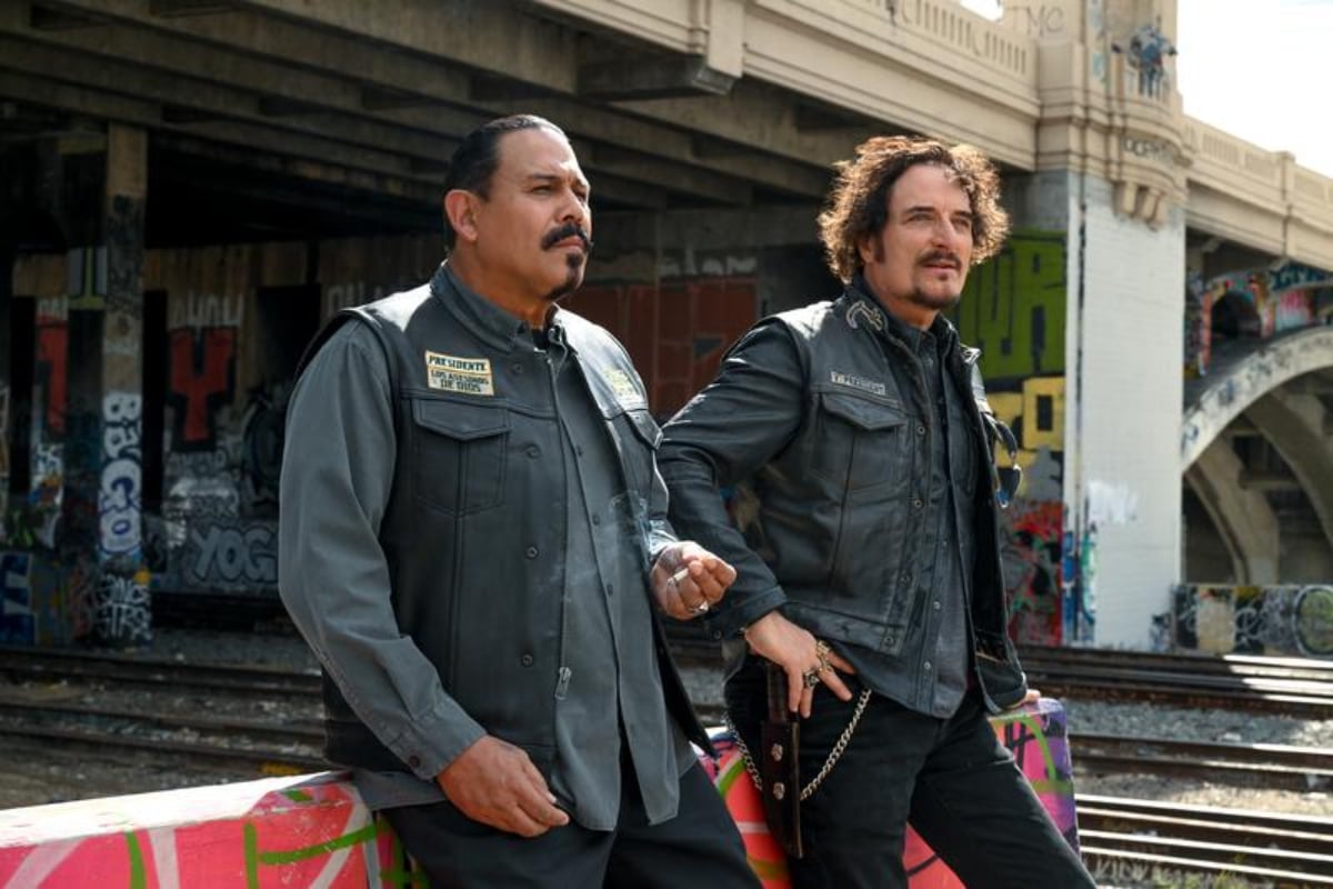 Marcus Alvarez and Tig Trager in the Mayans MC Season 4 finale. The pair stand next to each other wearing their biker kuttes. 