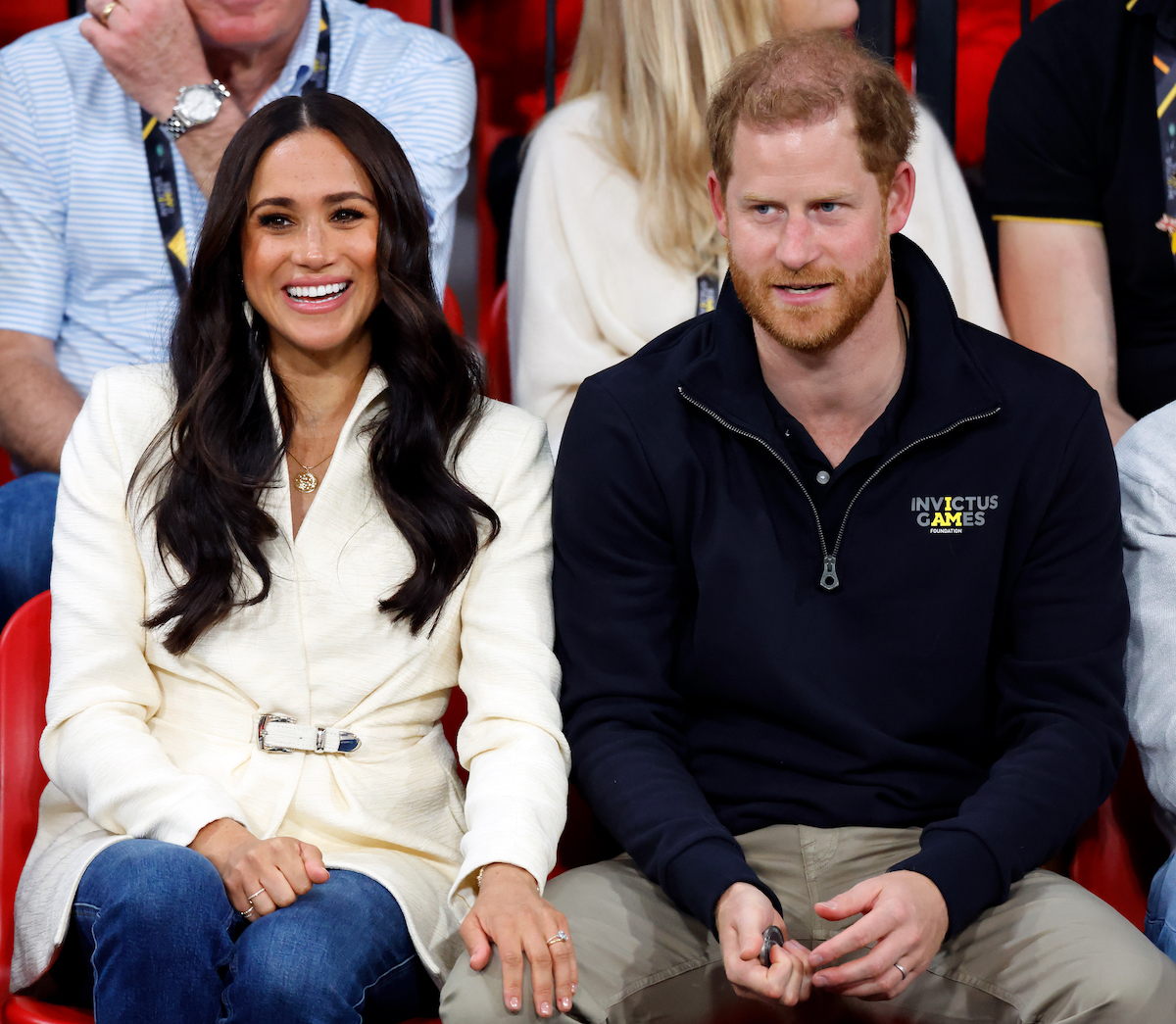 Meghan Markle and Prince Harry sit next to each other at an event.