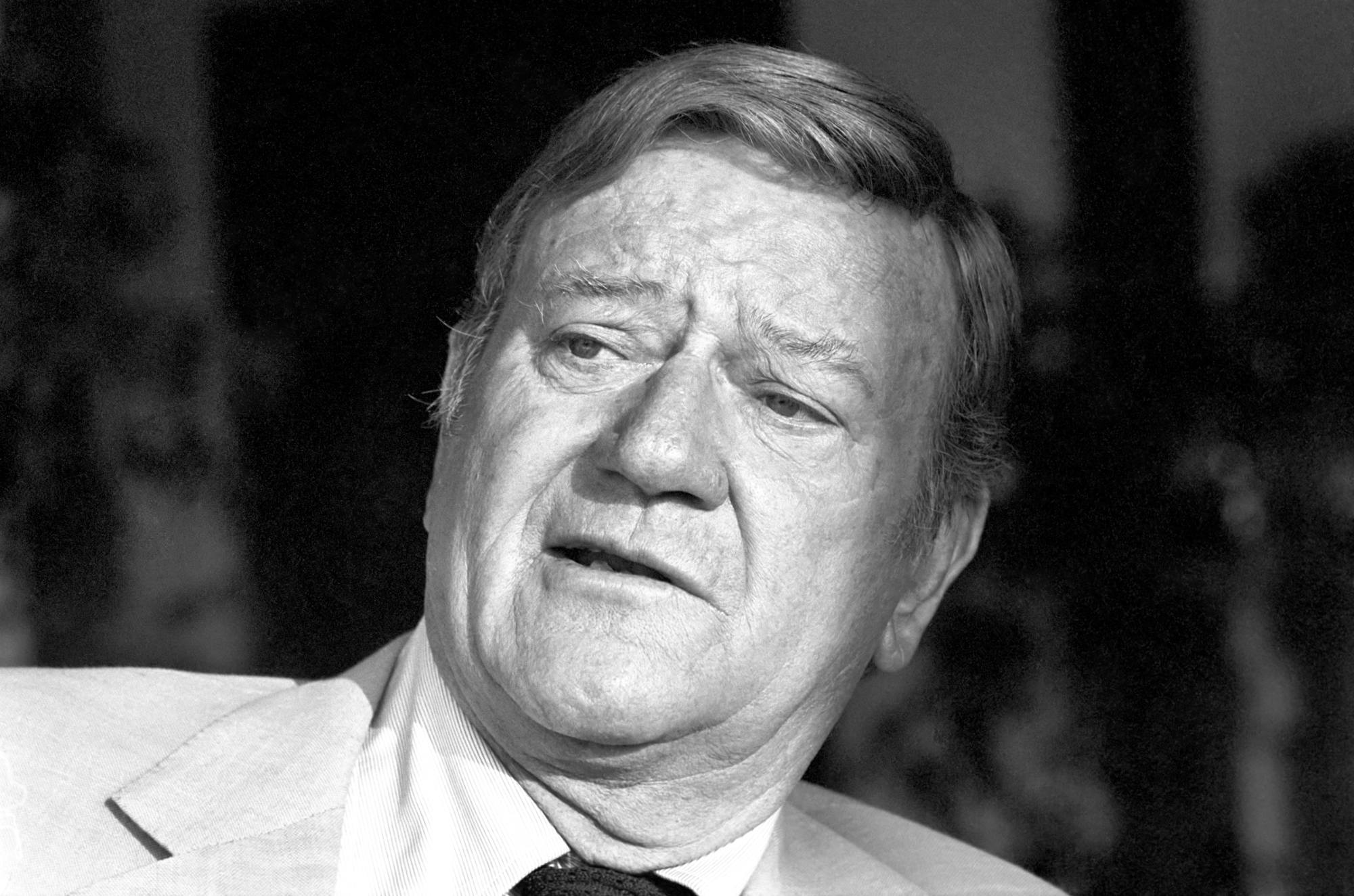 Movie star John Wayne in black-and-white photo wearing a suit