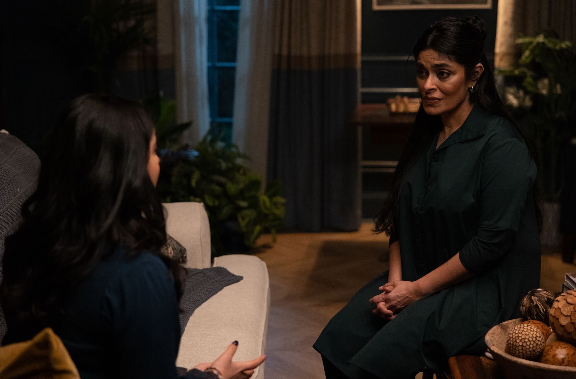 Iman Vellani and Nimra Bucha, in character as Kamala Khan and Najma in 'Ms. Marvel' Episode 3, which contains an MCU Easter egg, share a scene in a living room. Kamala wears a dark blue shirt. Najma wears a black jumpsuit.