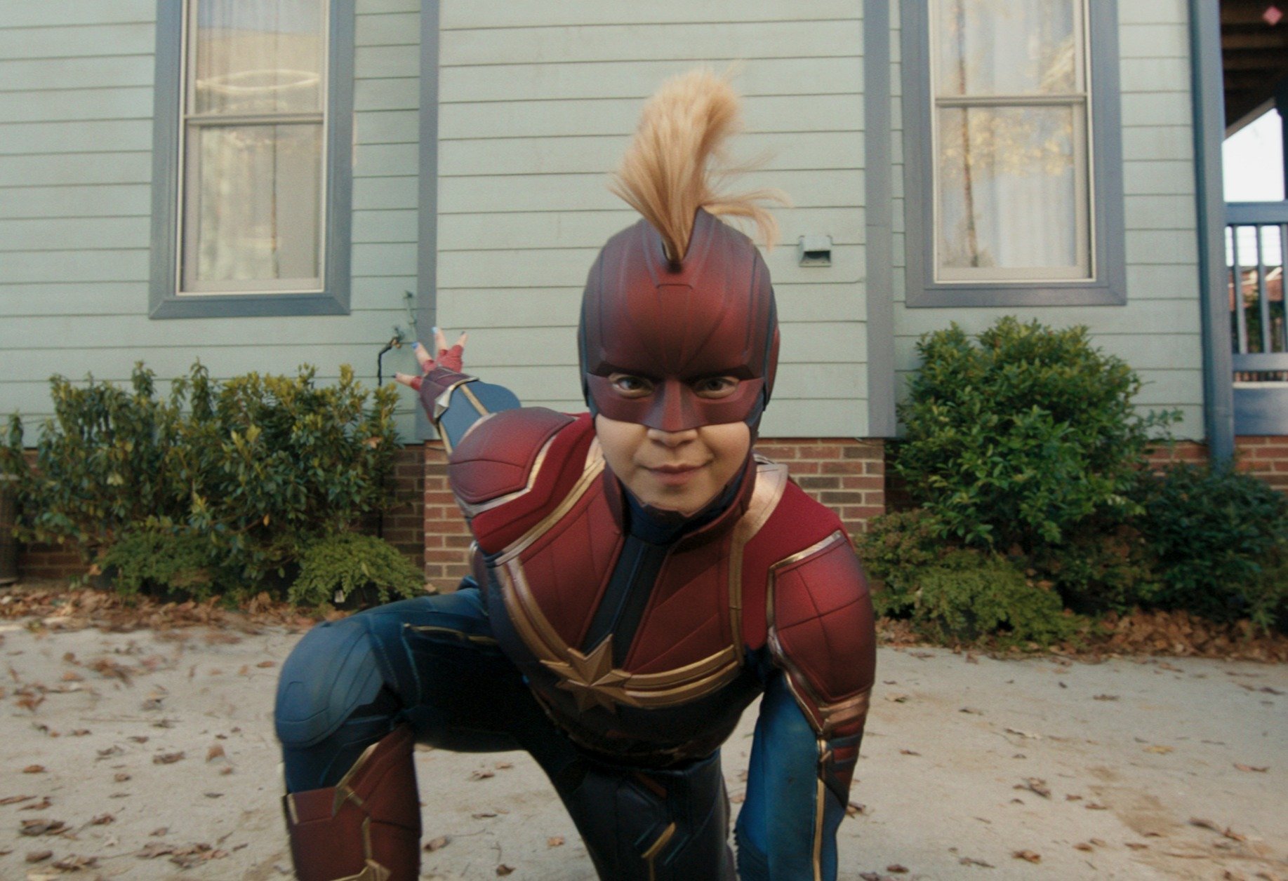 Iman Vellani as Kamala Khan in 'Ms. Marvel,' which has an episode 2 release date of June 15. She's wearing a Captain Marvel costume, and she's doing a superhero kneeling pose in front of her house.