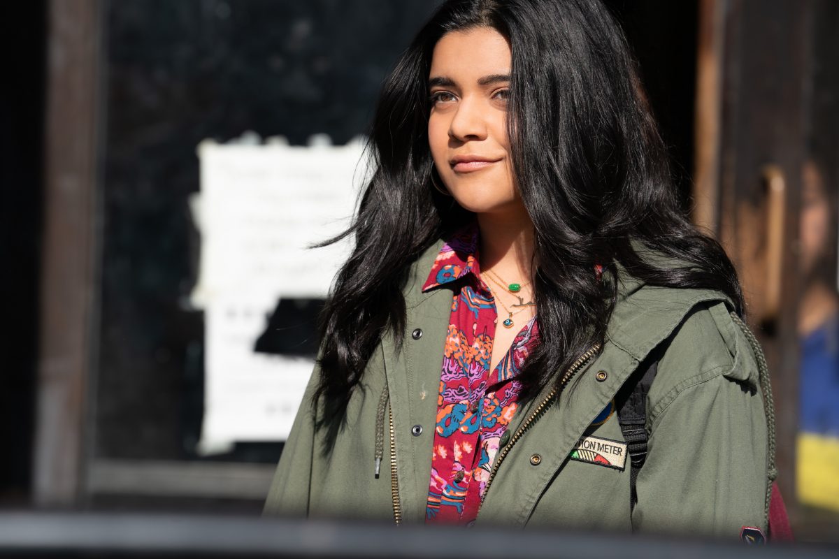 Iman Vellani in 'Ms. Marvel,' which has an episode 3 release date of June 22. She's wearing a green jacket and her hair is down.