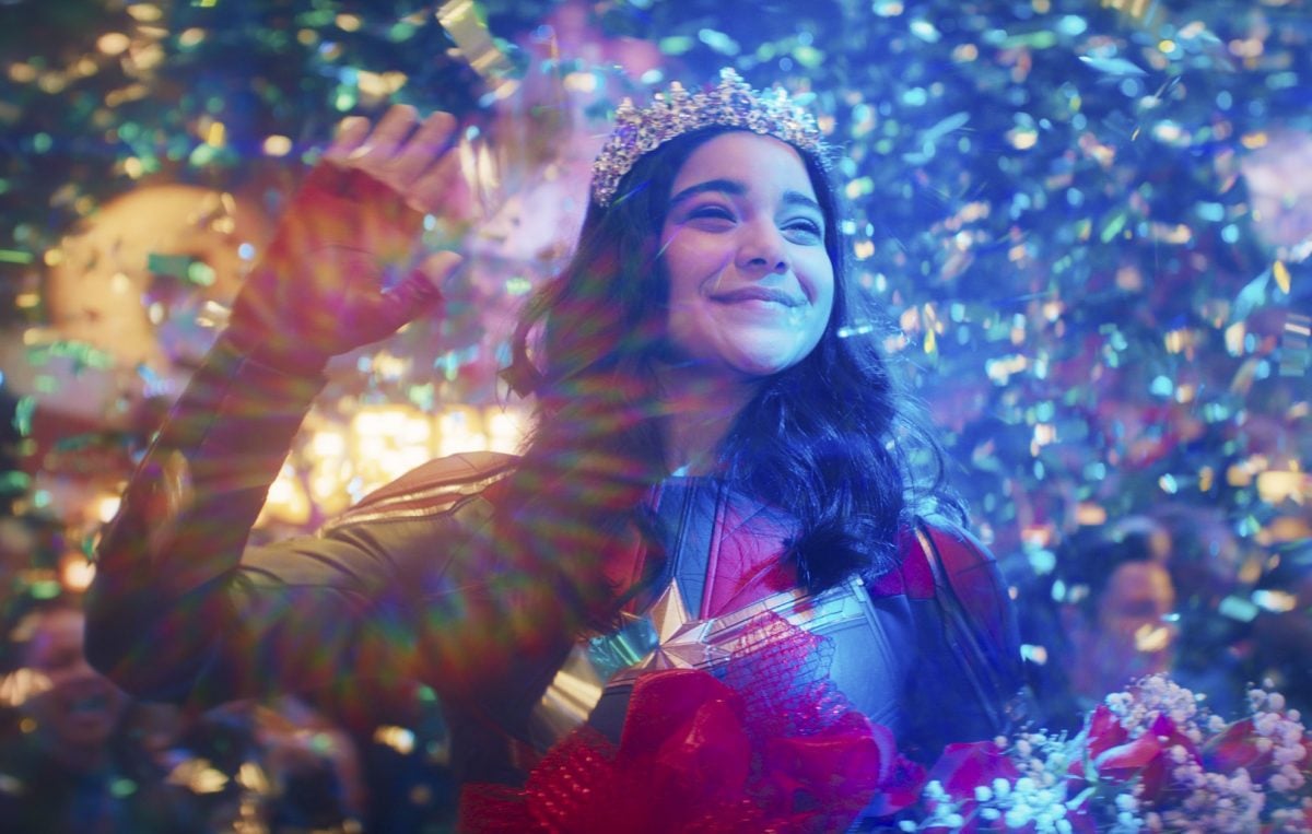 Iman Vellani in 'Ms. Marvel,' which will span six episodes on Disney+. She's wearing a tiara, waving, and appears to have won something.