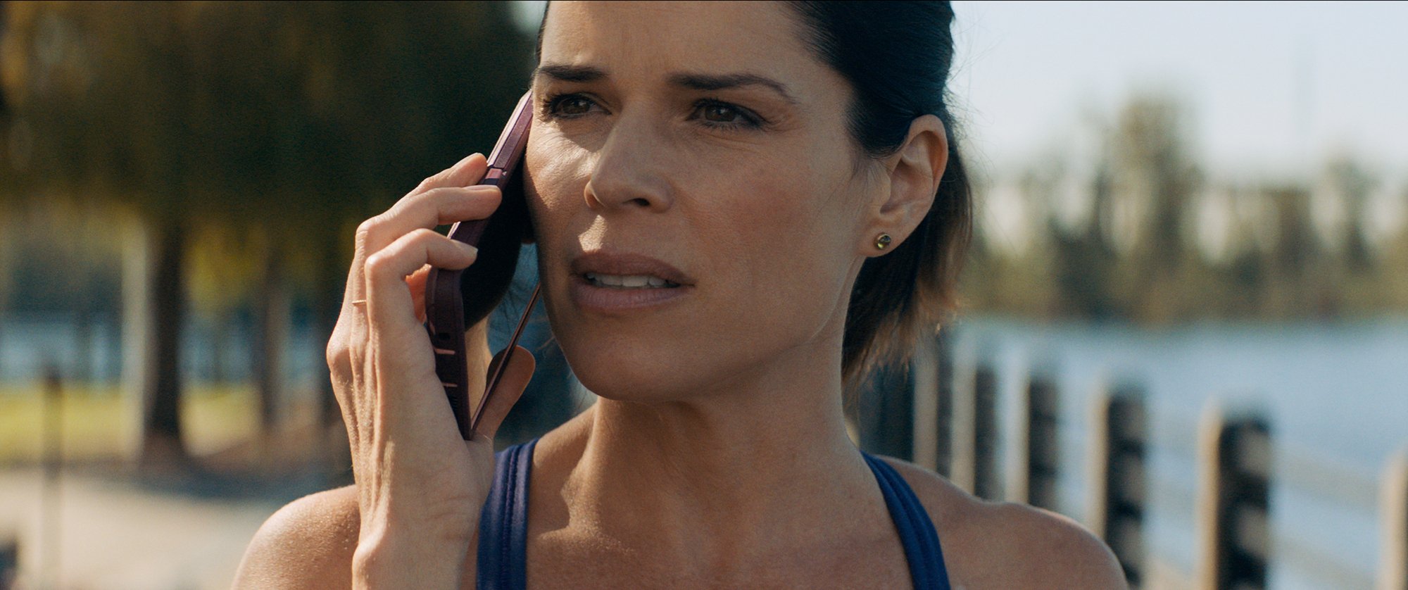 Neve Campbell as Sidney Prescott, who exited 'Scream 6,' looking concerned on a pink cell phone