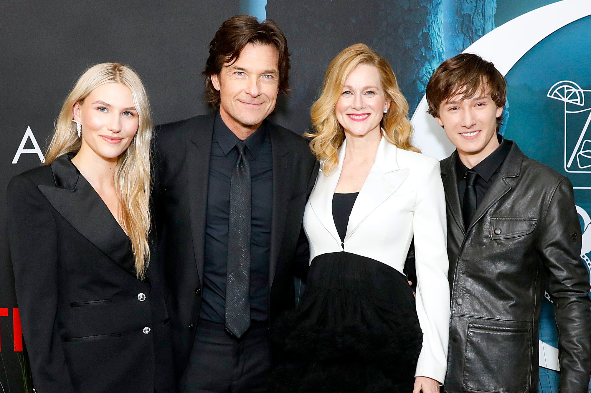 Cast members Sofia Hublitz, Jason Bateman, Laura Linney, and Skylar Gaertner attend the premiere of 'Ozark' Season 4. They're wearing formal clothes and standing next to one another, smiling.