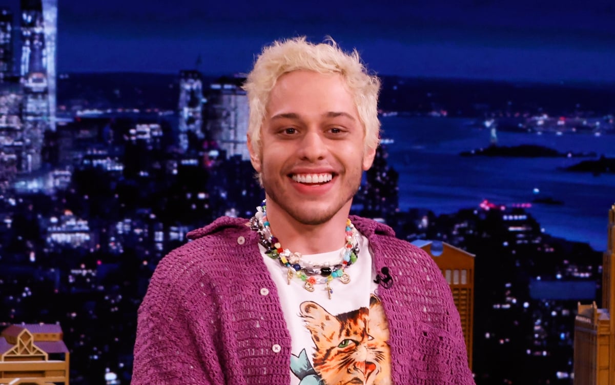 Comedian Pete Davidson on 'The Tonight Show Starring Jimmy Fallon', Season 8 wearing a pink cardigan and a cat T-shirt.