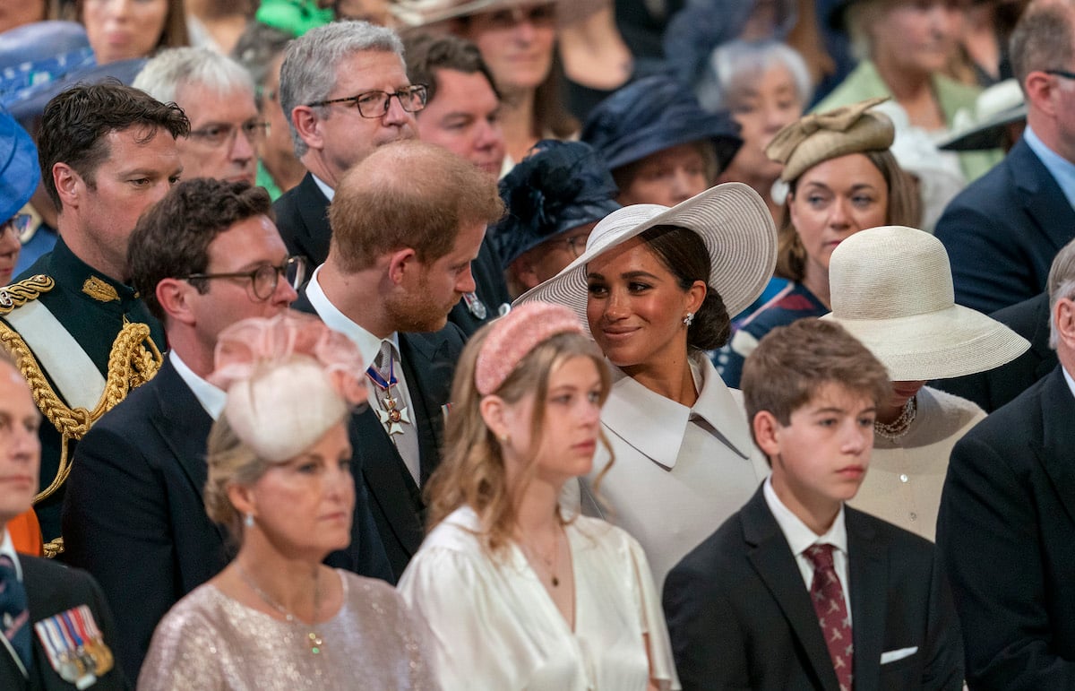 Prince Harry and Meghan Markle, who a lip reader says had four words for Prince Harry, sit next to each other at a jubilee service
