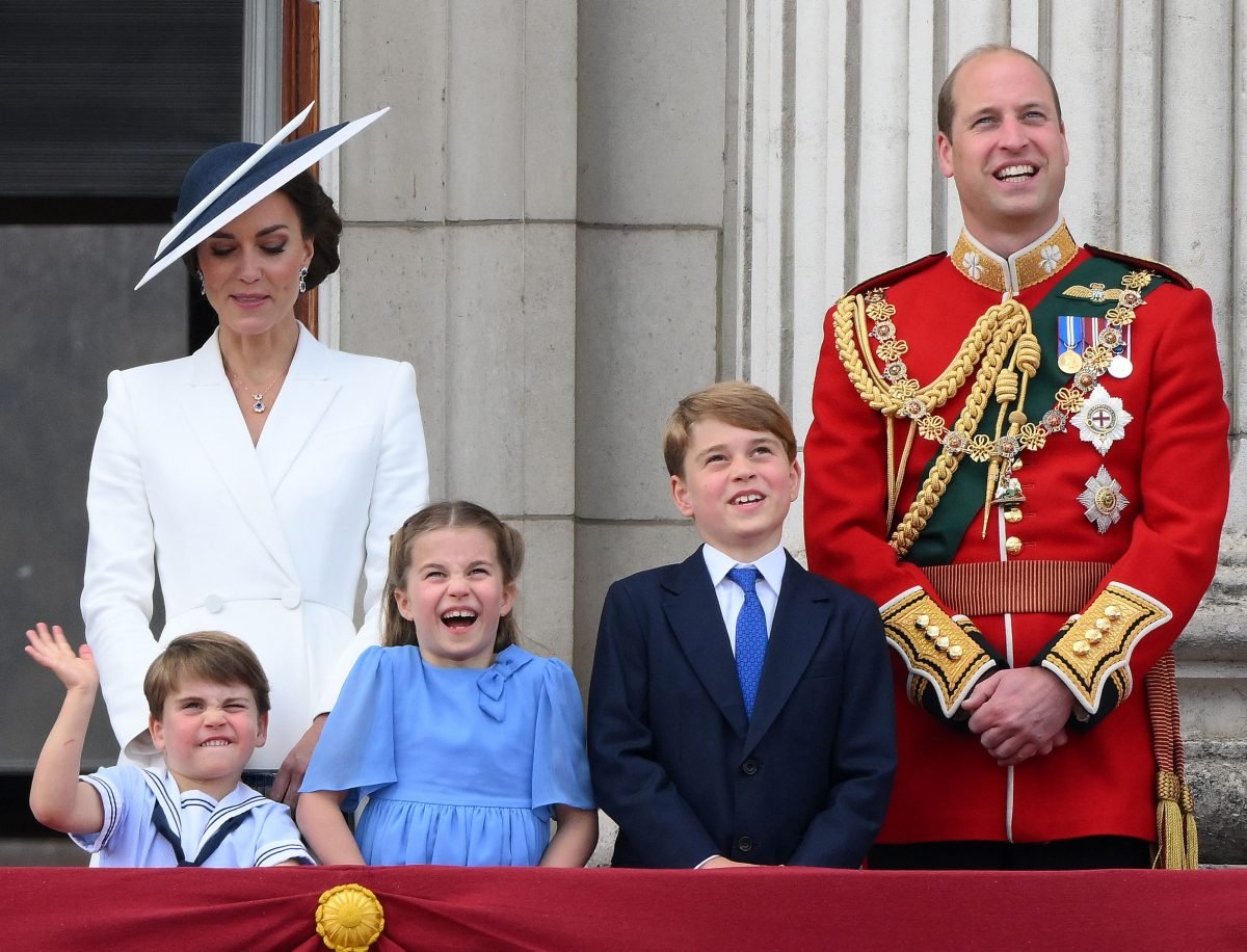 Prince William and Kate Middleton standing with their children while watching a special flypast from Buckingham Palace balcony