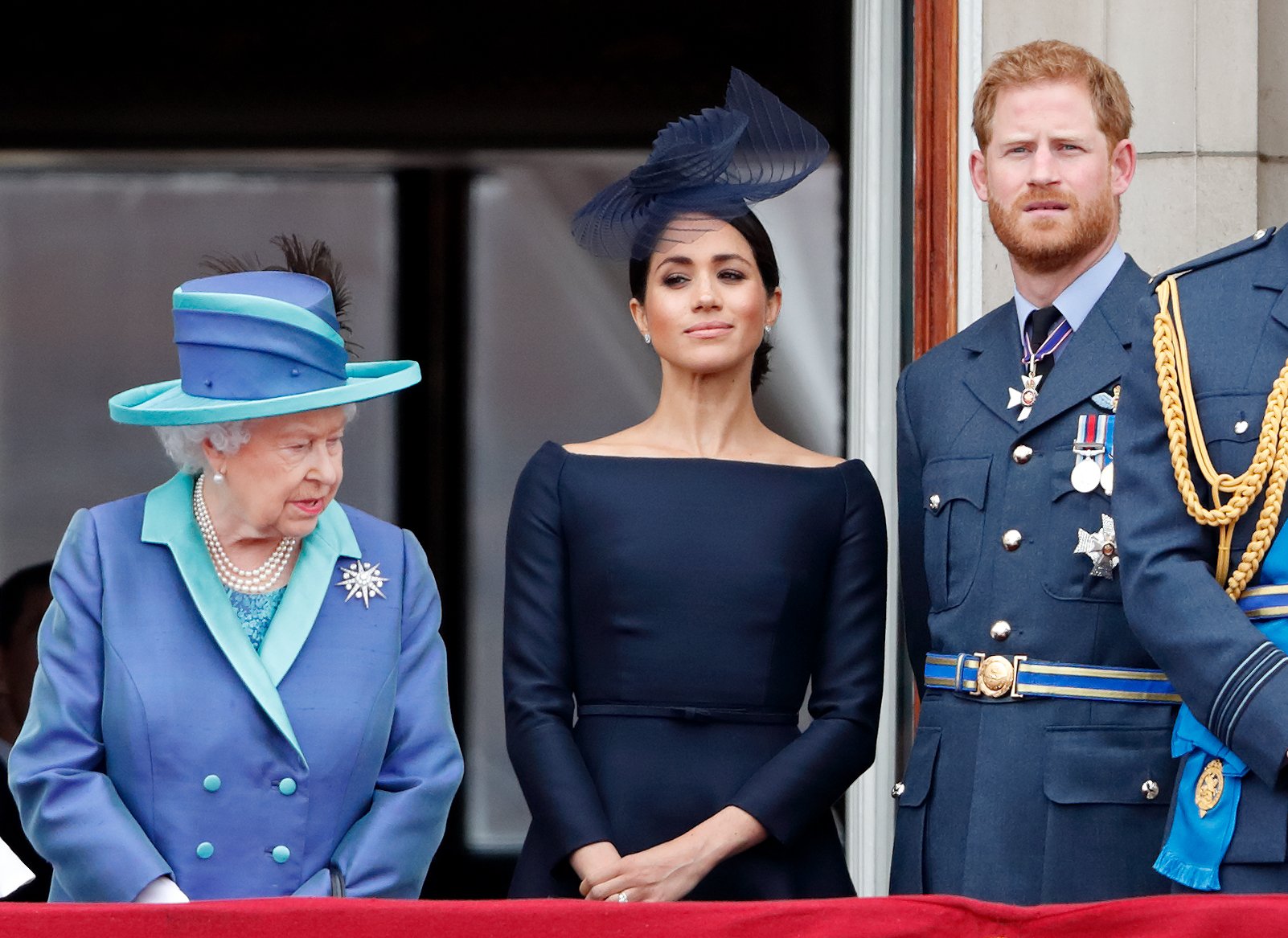 Queen Elizabeth II, Meghan Markle, and Prince Harry standing on the balcony of Buckingham Palace