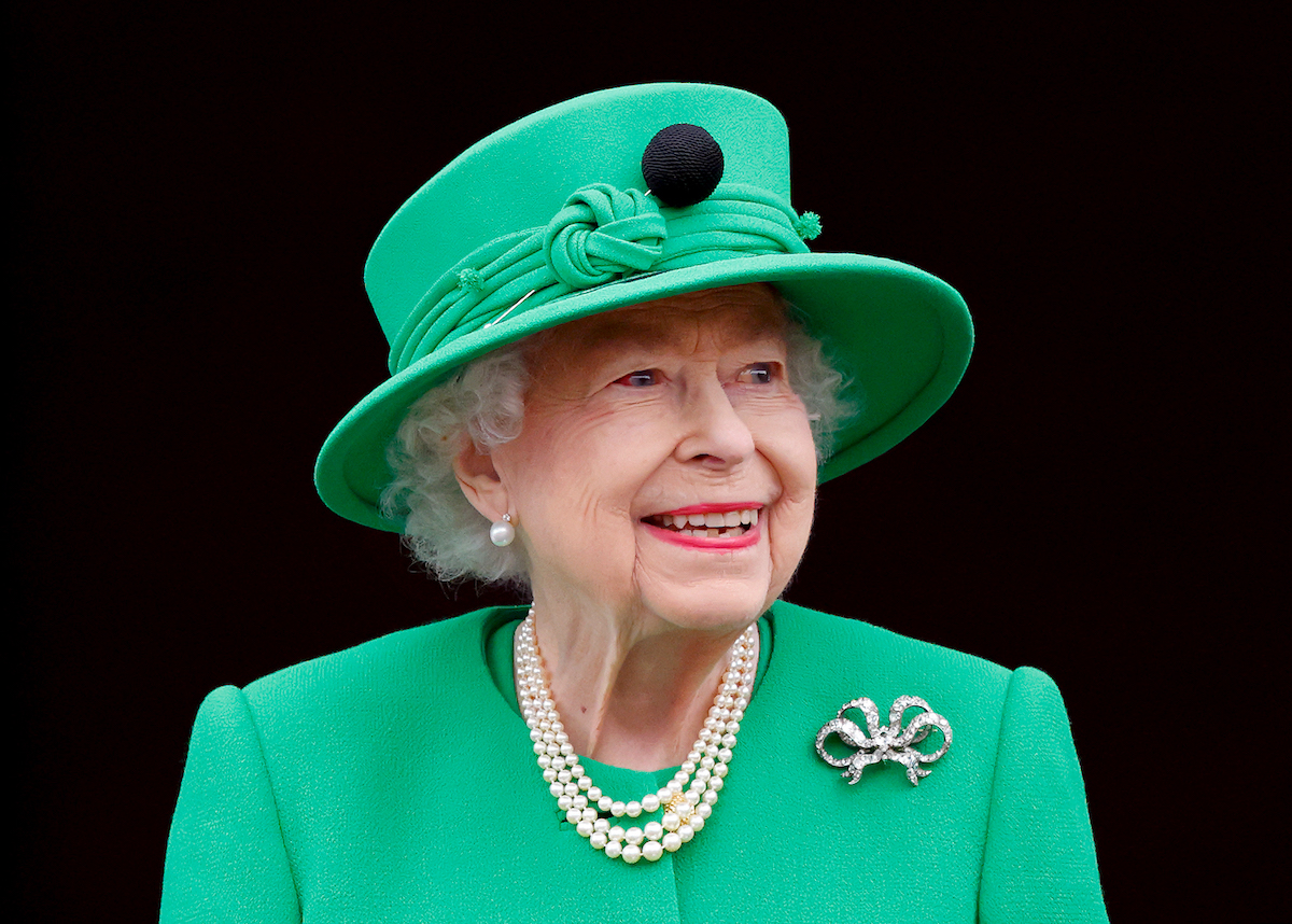 Queen Elizabeth II, who wasn't featured in a photo with Lili, smiles and looks on wearing a green suit and hat