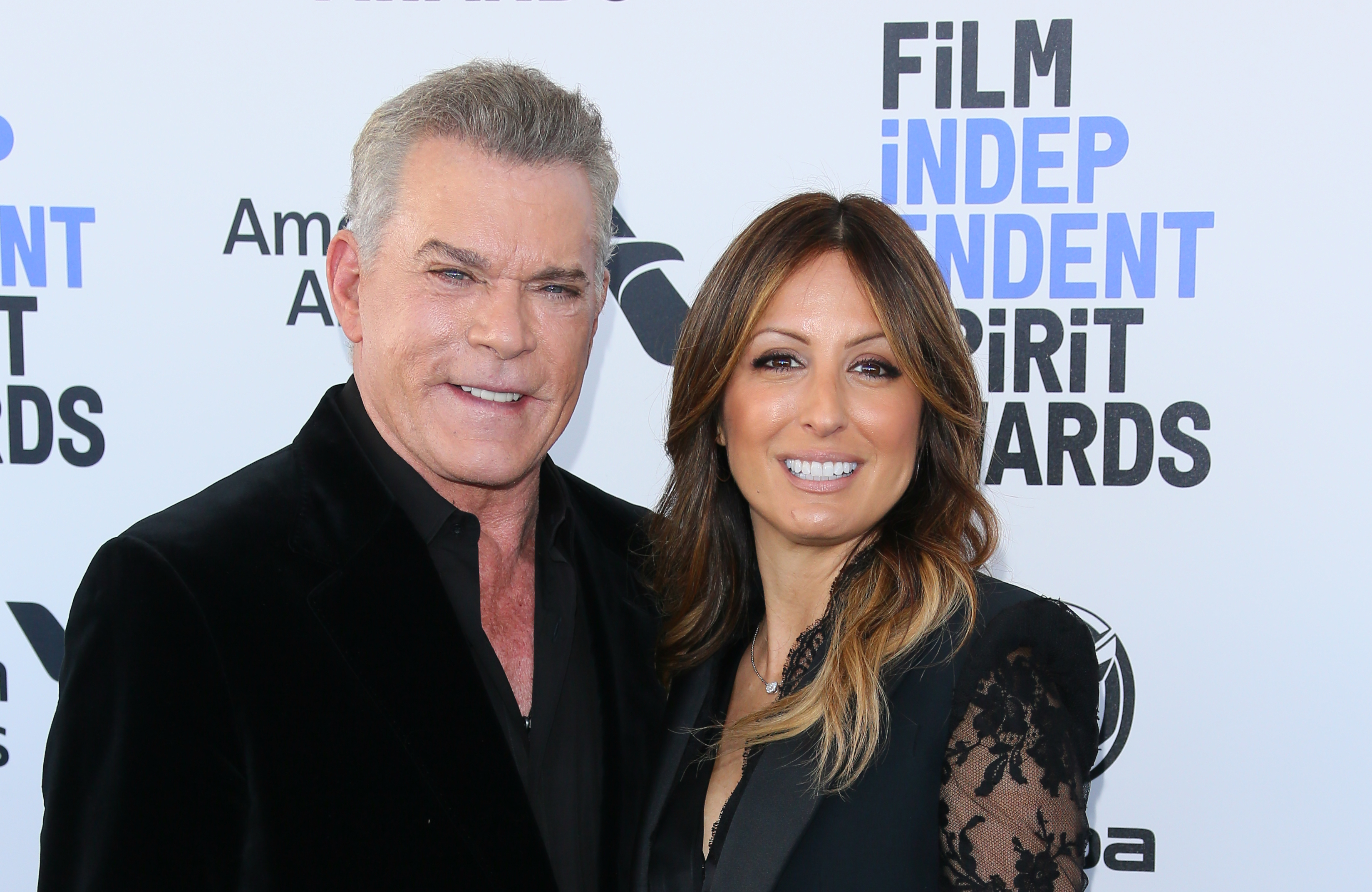 Ray Liotta and his fiancee, Jacy Nittolo, smile together on the red carpet at the Film Independent Spirit Awards