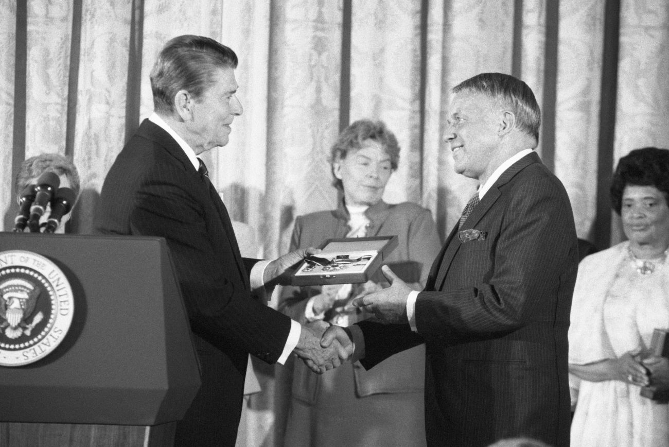 A black and white picture of Ronald Reagan and Frank Sinatra shaking hands.