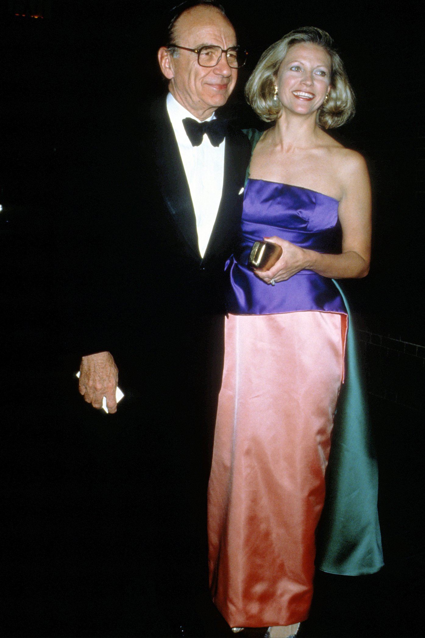Rupert Murdoch and wife Anna Murdoch Mann circa 1989 standing with their arms around each other in formal attire