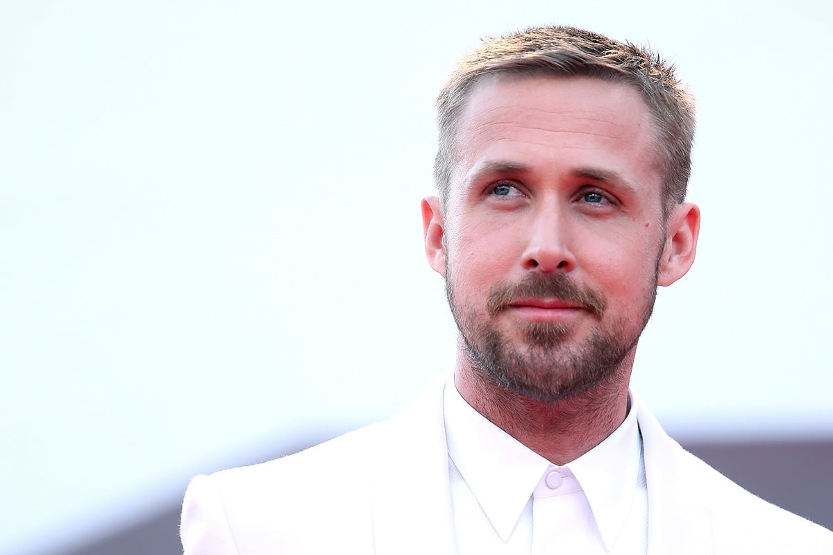 Ryan Gosling smirking while wearing a white suit.