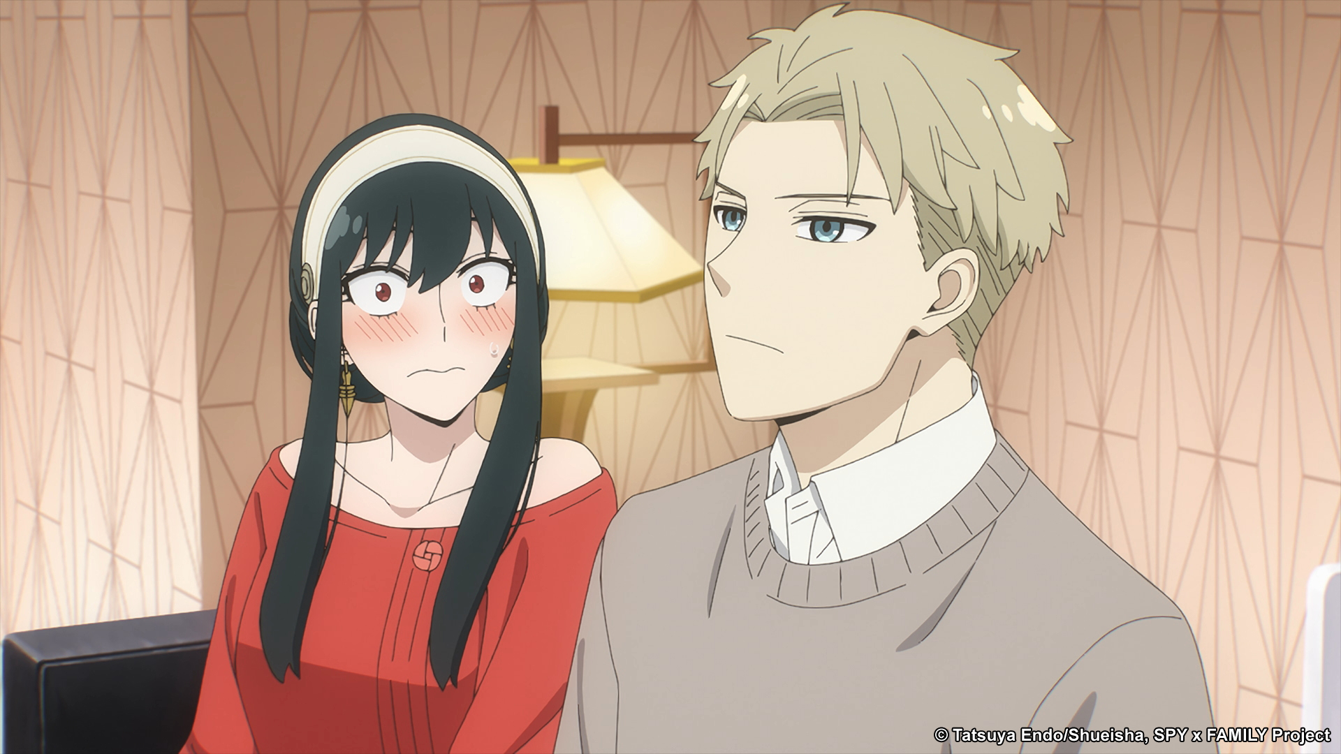Yor and Loid Forger, both of whom will return on the release date for 'Spy x Family' Episode 10. They're sitting on the couch, and Yor is looking at Loid and blushing.