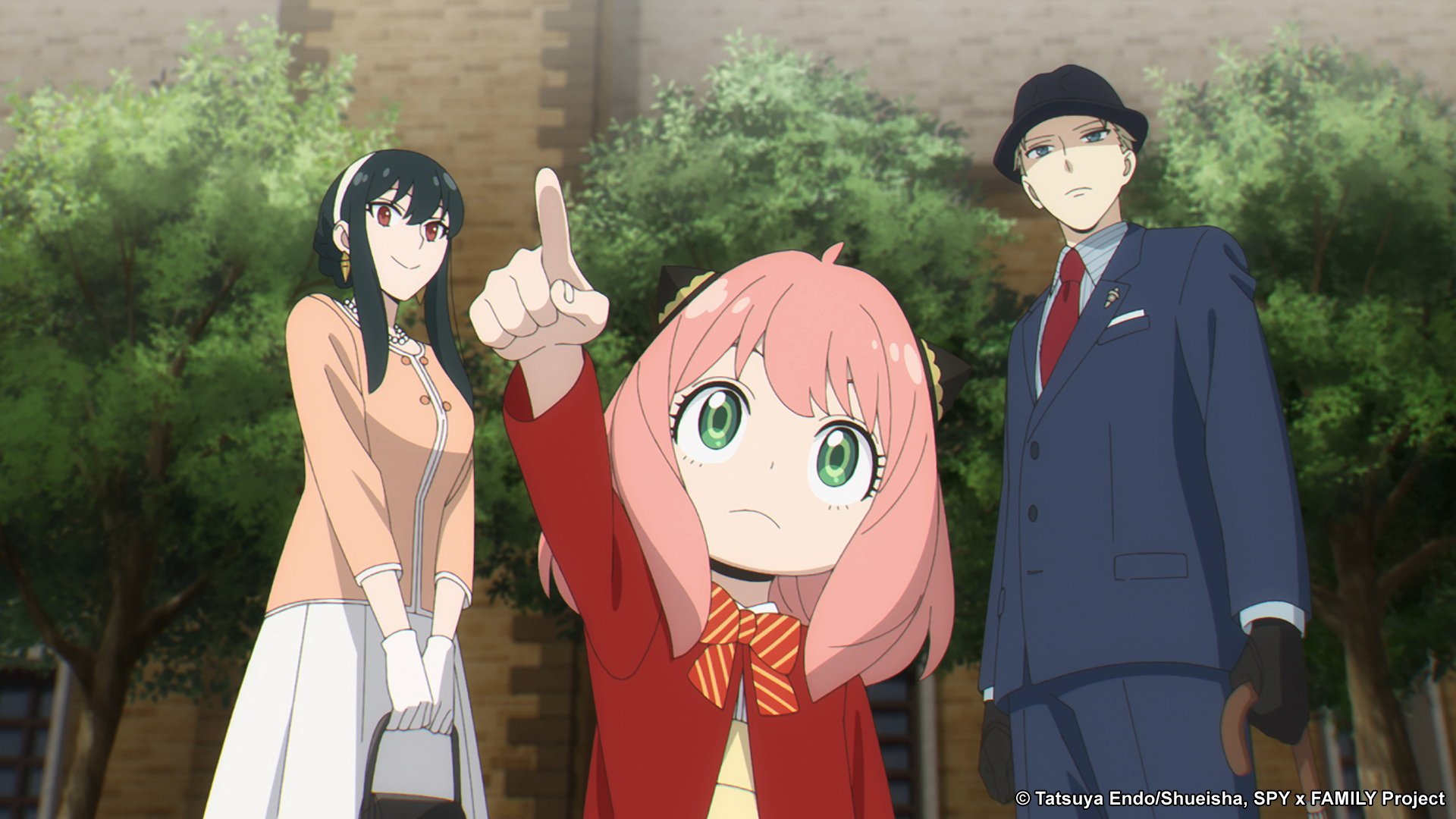 Yor, Anya, and Loid in 'Spy x Family,' which returns for season 1 part 2 in October. Anya is wearing a red uniform, standing in front of her parents, and pointing up at something.
