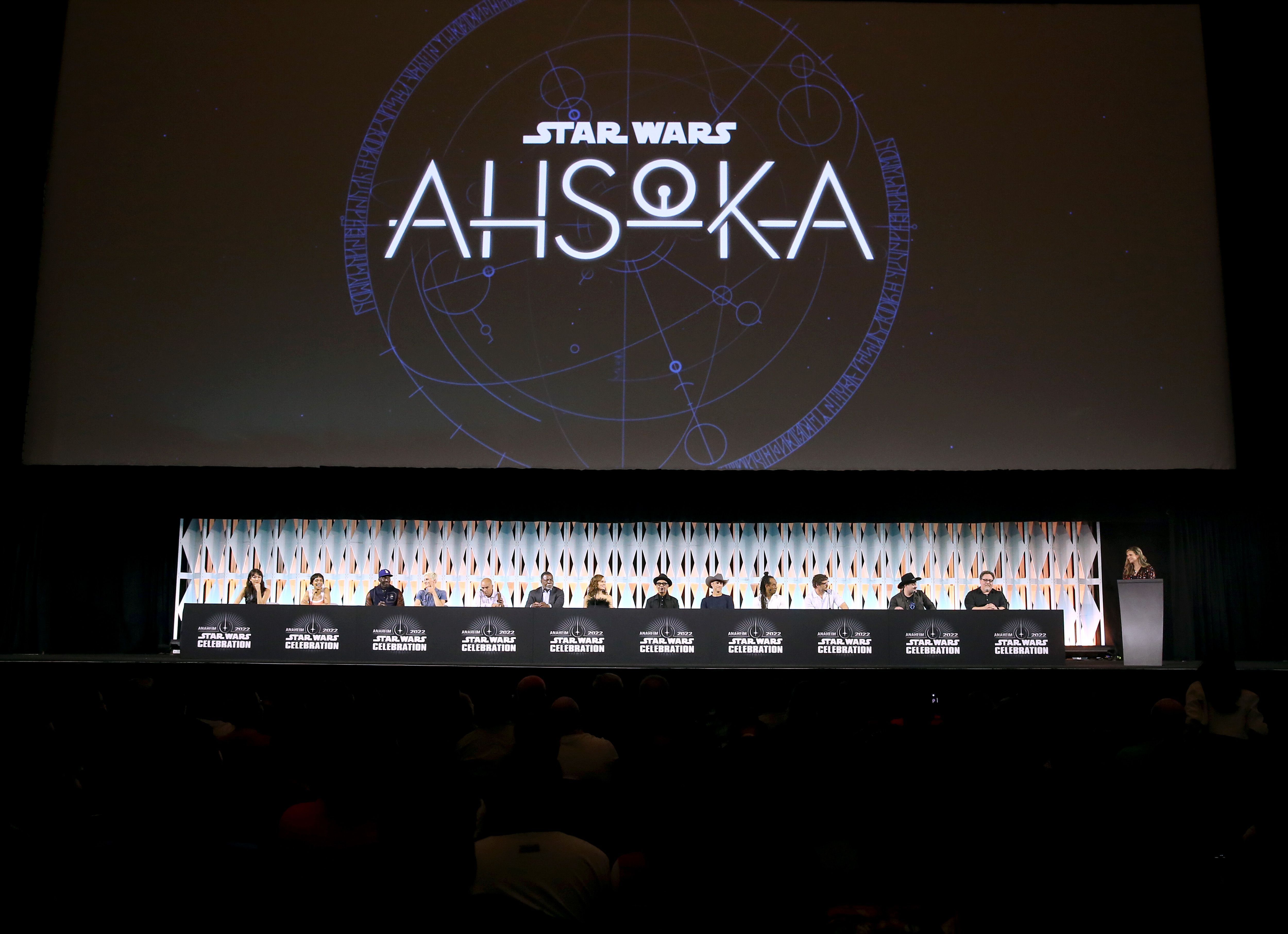 Actors seated on stage for a panel on 'Star Wars' shows streaming on Disney+ under an image with the logo for the series 'Ahsoka.'