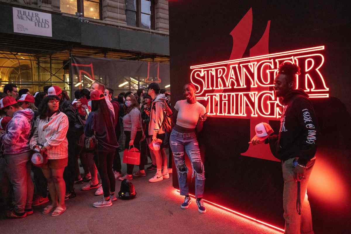People pose by the "Stranger Things 4" logo at a 2022 global fan event in New York