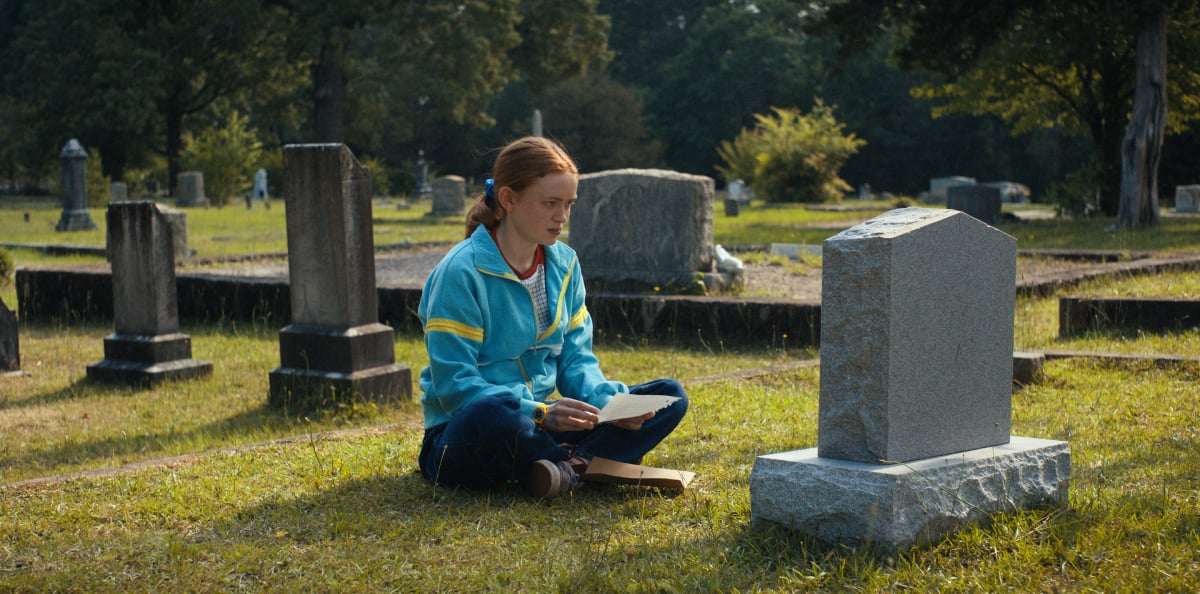 Sadie Sink as Max Mayfield in Stranger Things Season 4. Max reads her letter in front of Billy's grave. 
