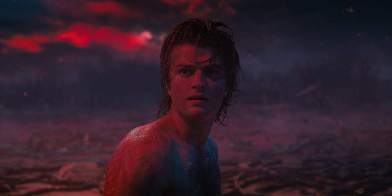 Joe Keery as Steve Harrington in 'Stranger Things' is in the Upside Down looking at the dark sky.